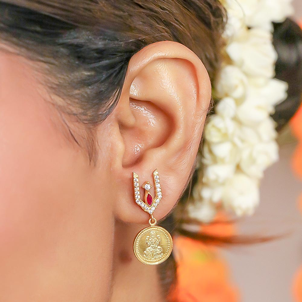 Close-up of Unniyarcha silver earrings with intricate filigree work, photographed on a fabric backdrop with soft lighting