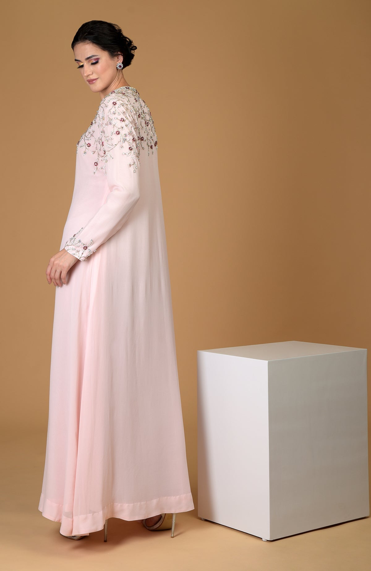 A woman models a pale pink hand-embroidered dress with crystal and bead details.