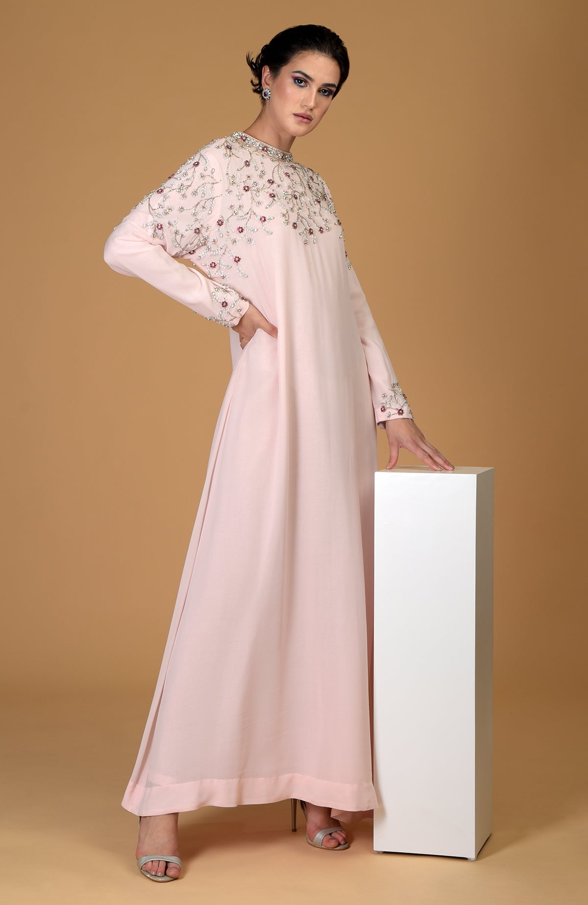 A model wears a pale pink hand-embroidered dress with crystal and bead embellishments.