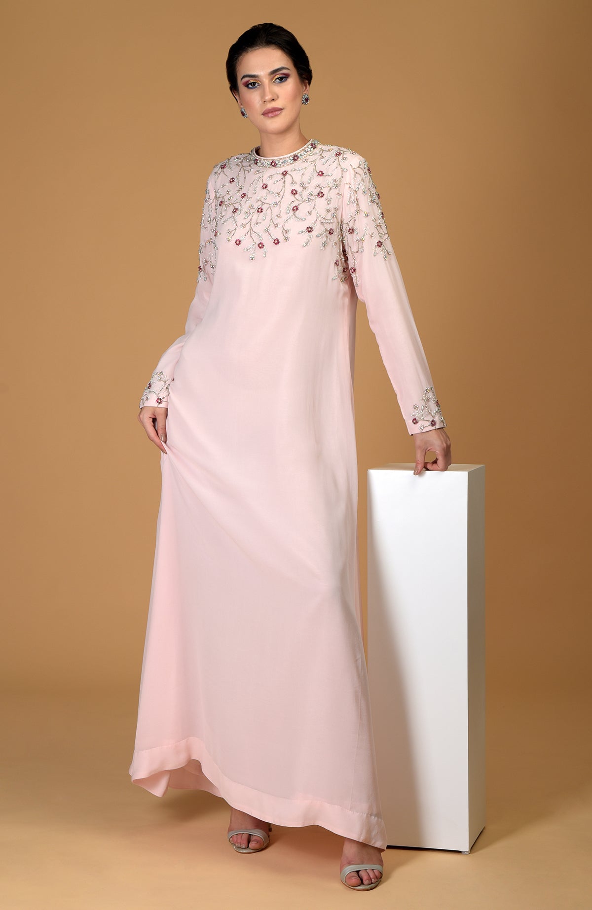 A woman models a pale pink hand-embroidered dress with crystal and bead floral patterns.