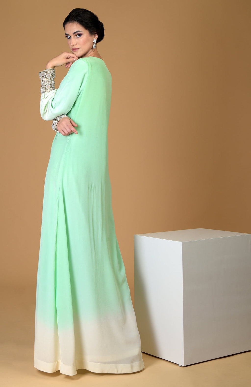 A woman models a sage green ombre dress with sparkling jeweled cuffs.
