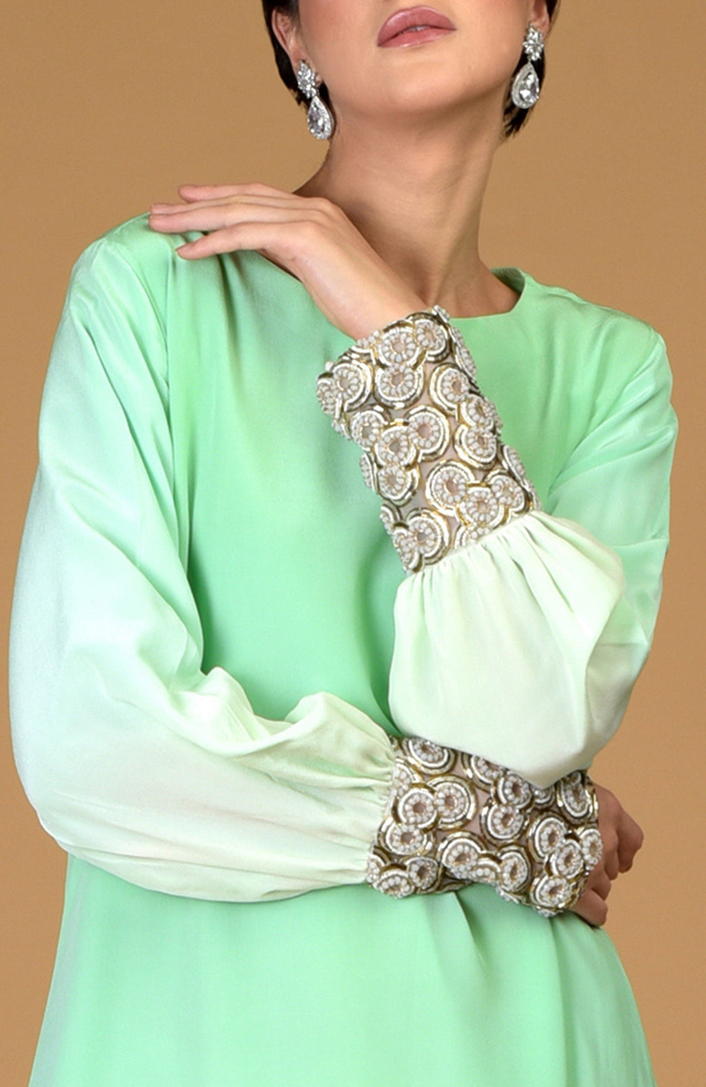 An ombre sage green silk crepe dress with sparkling circular jeweled cuffs.