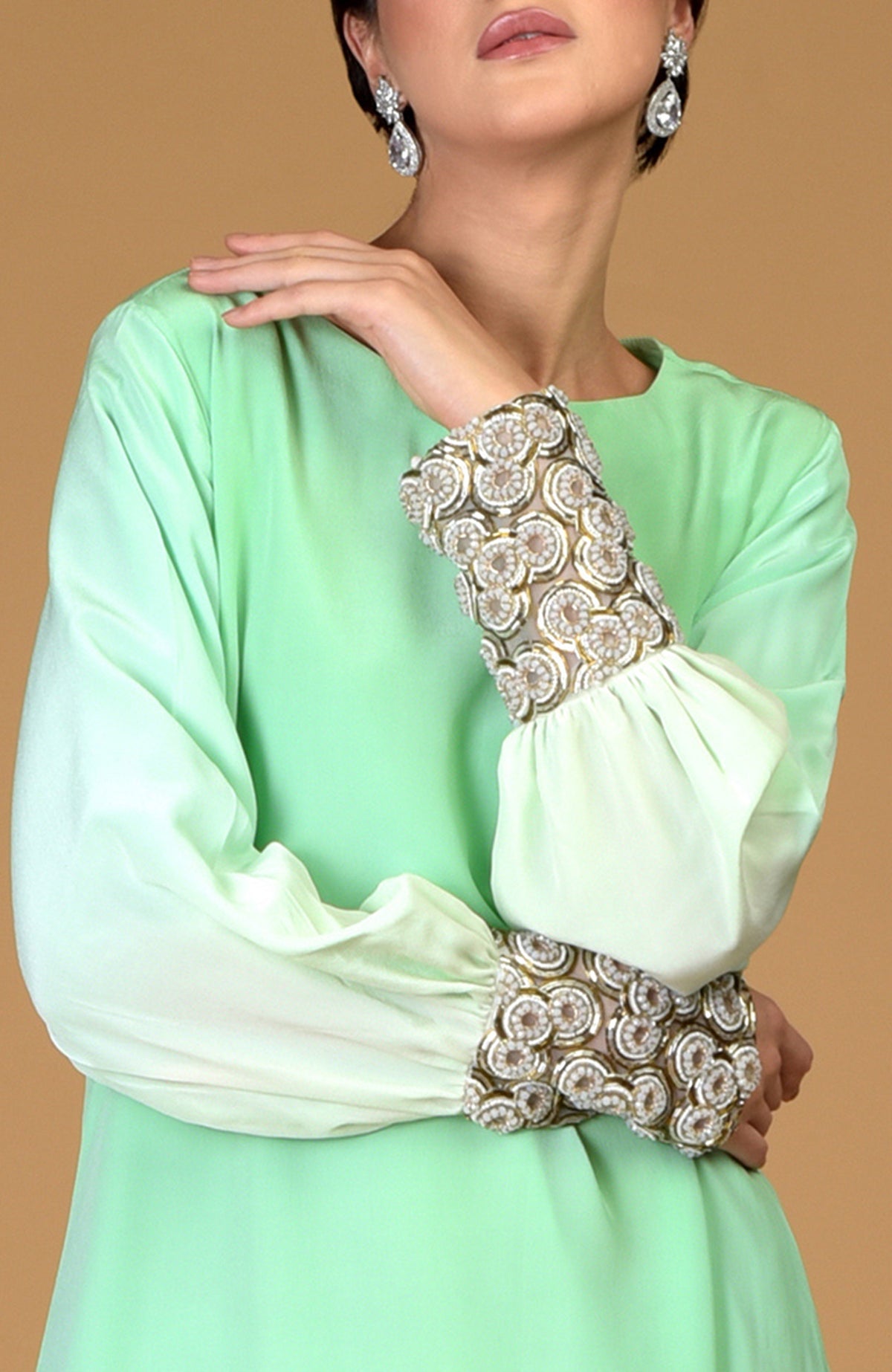 An ombre sage green silk crepe dress with sparkling circular jeweled cuffs.