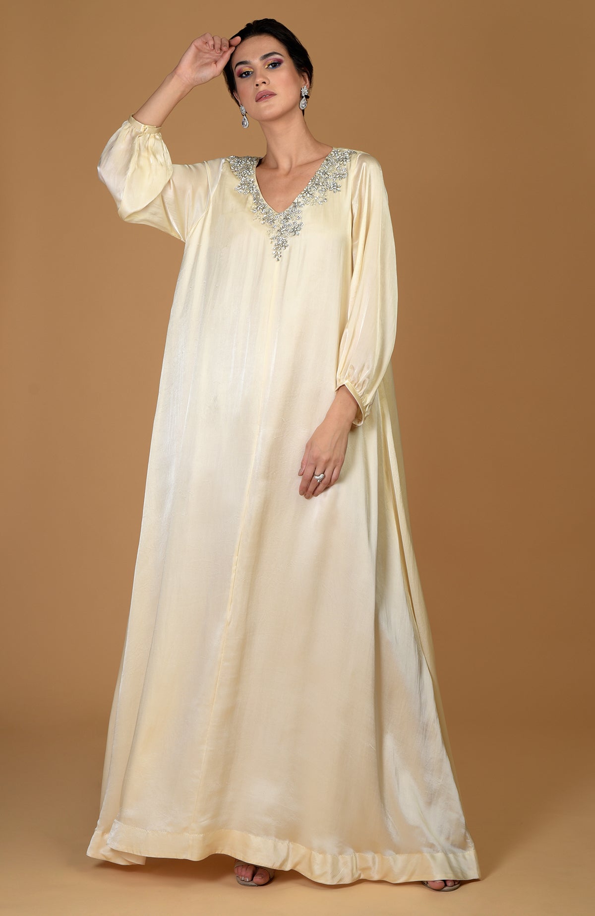 A woman models a white gold dress with crystal cluster hand embroidery.
