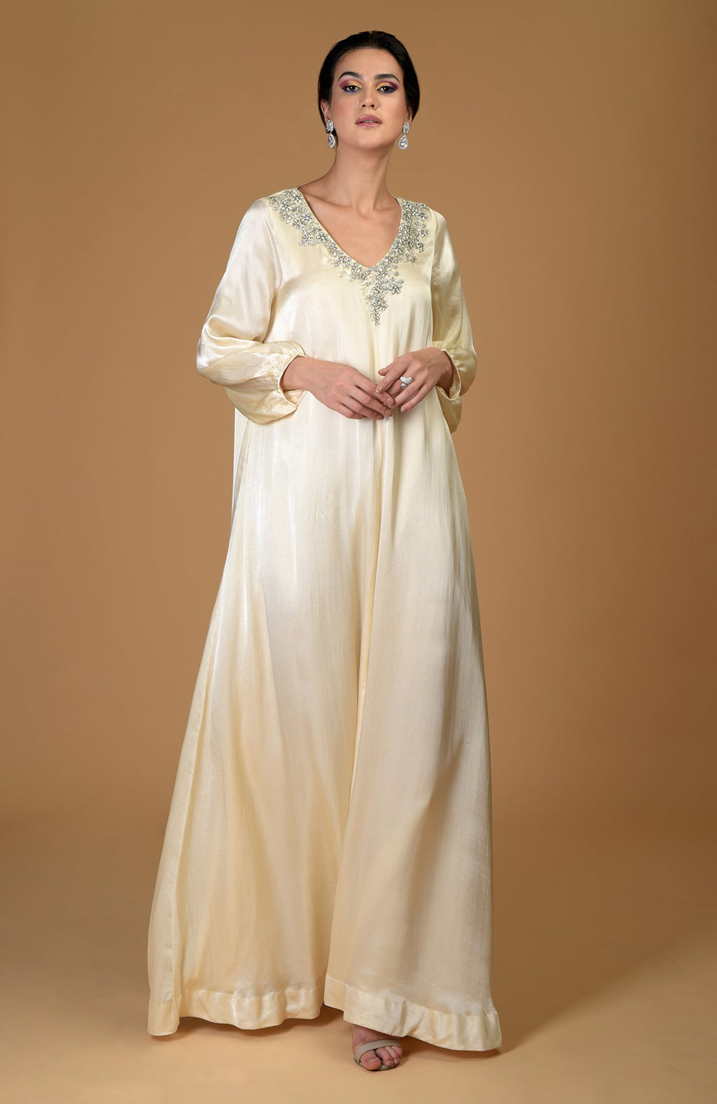 A woman models a white gold hand-embroidered dress with crystal clusters on the neckline.