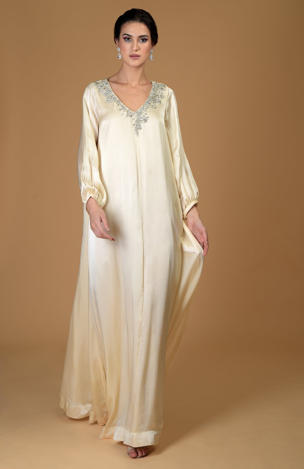 A woman models a white gold hand-embroidered dress with crystal clusters.
