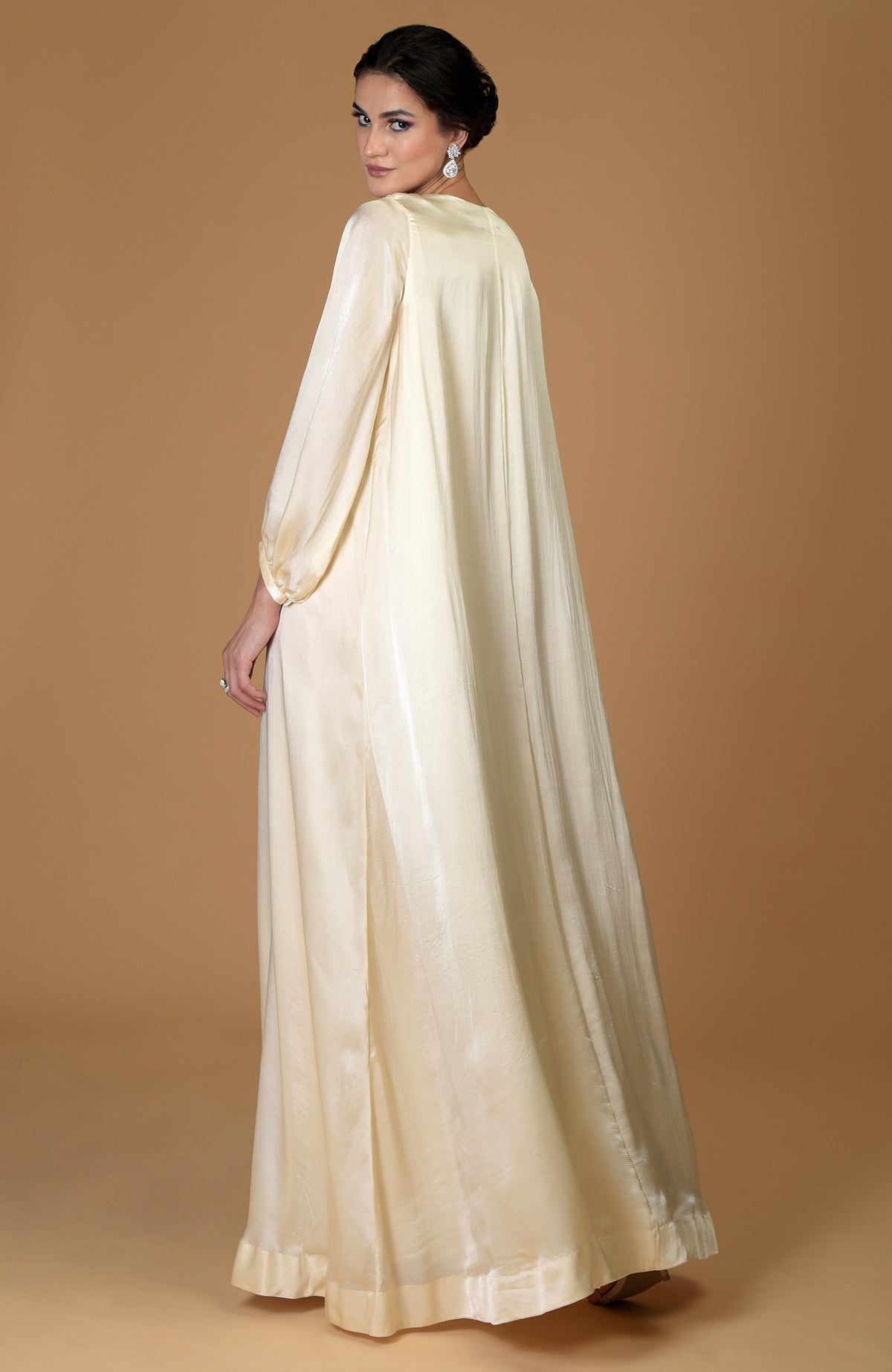 A woman in a white gold crystal cluster hand-embroidered dress looks over her shoulder.