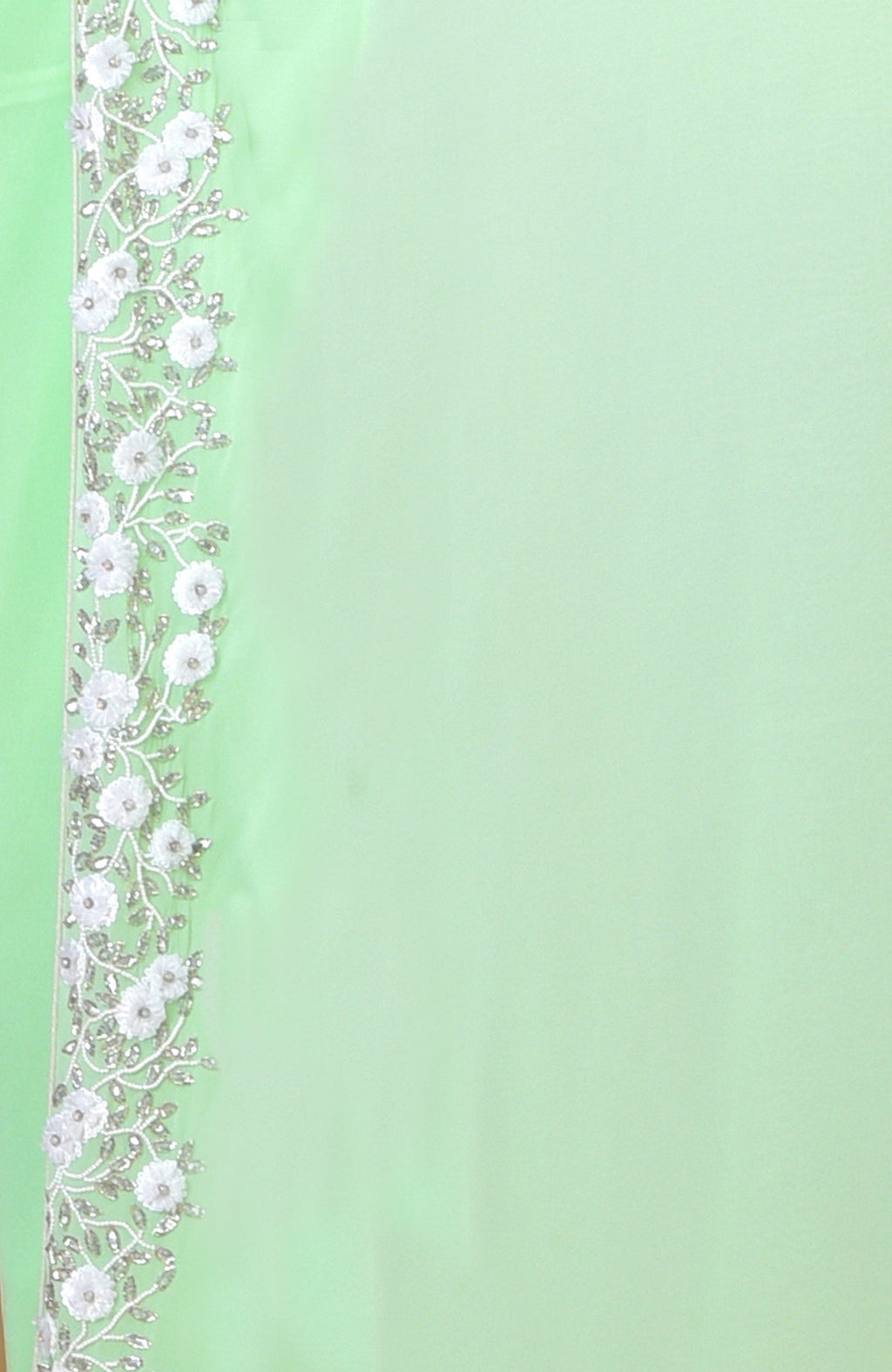 Mint green dress with white floral and silver vine embroidery along the left edge.