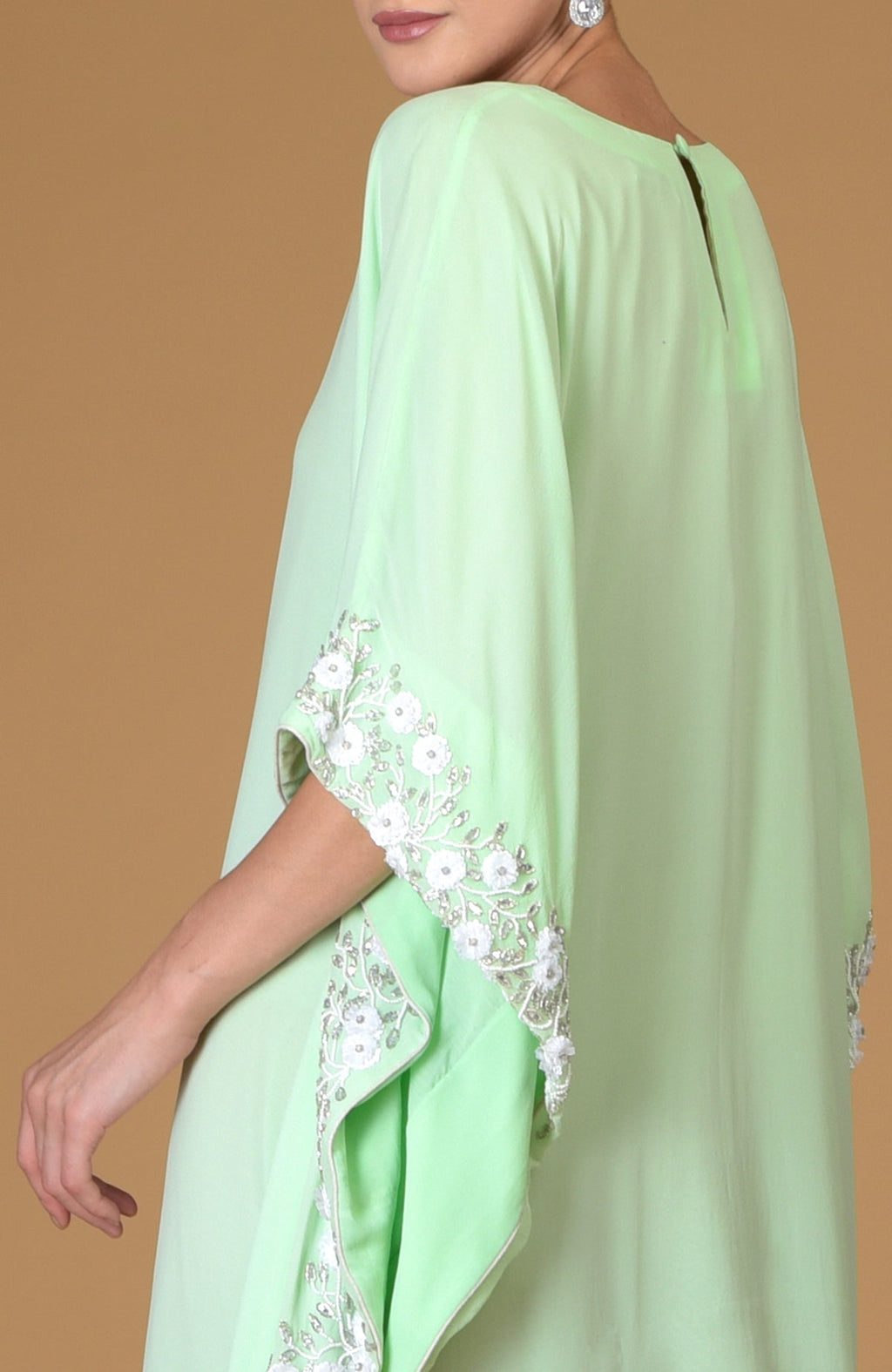 Mint green kaftan dress with white floral and vine hand embroidery on the sleeves.