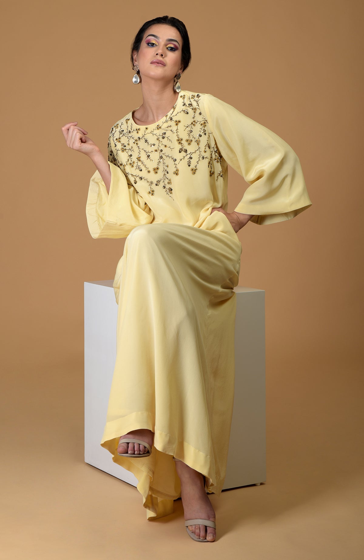 A woman models a lemon yellow dress with dainty floral hand embroidery.