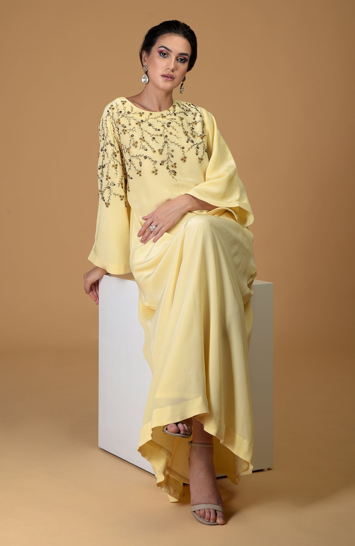 A woman models a lemon yellow dress with dainty floral embroidery.