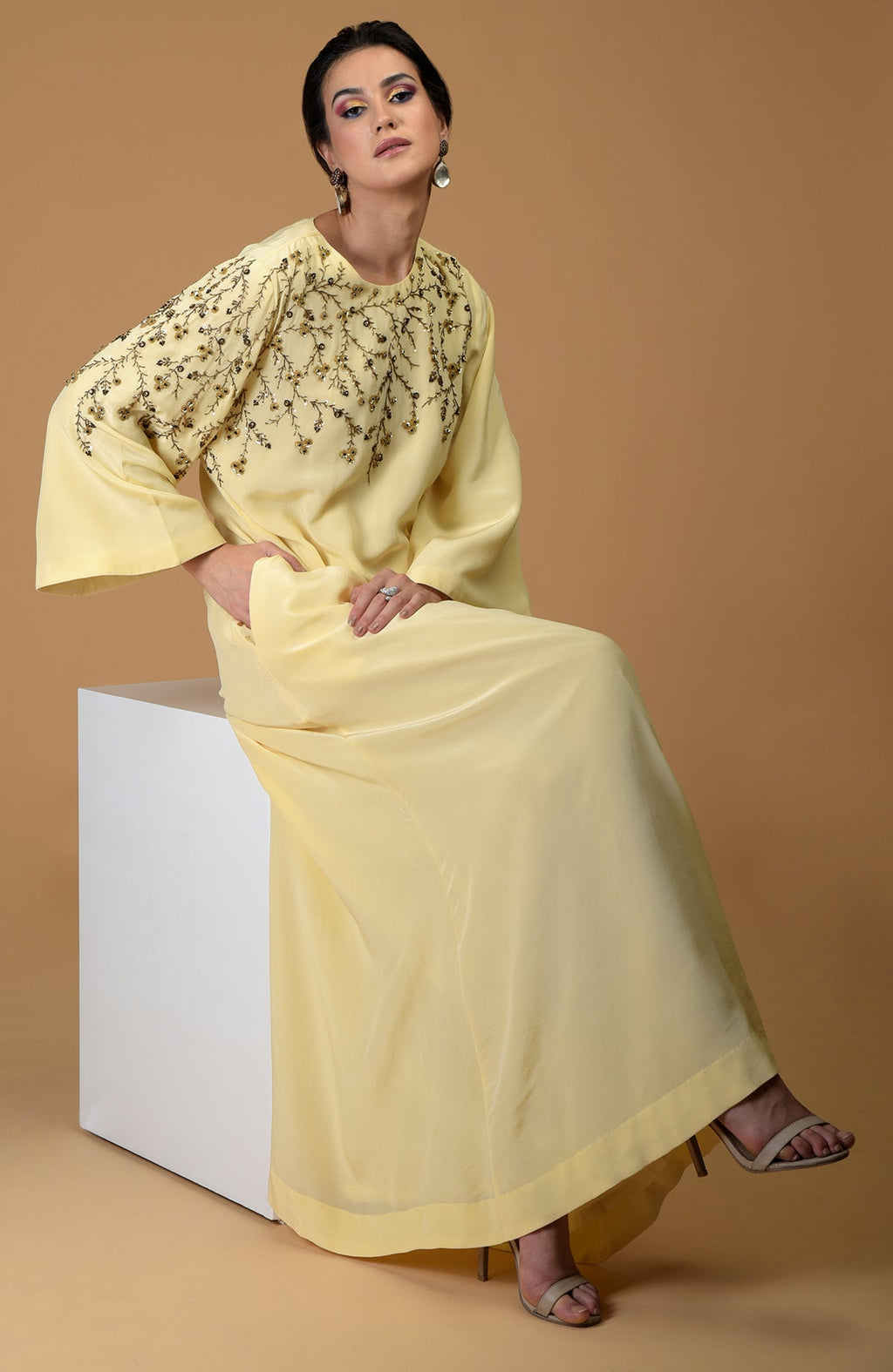 A woman models a lemon yellow dress with dainty floral hand embroidery.