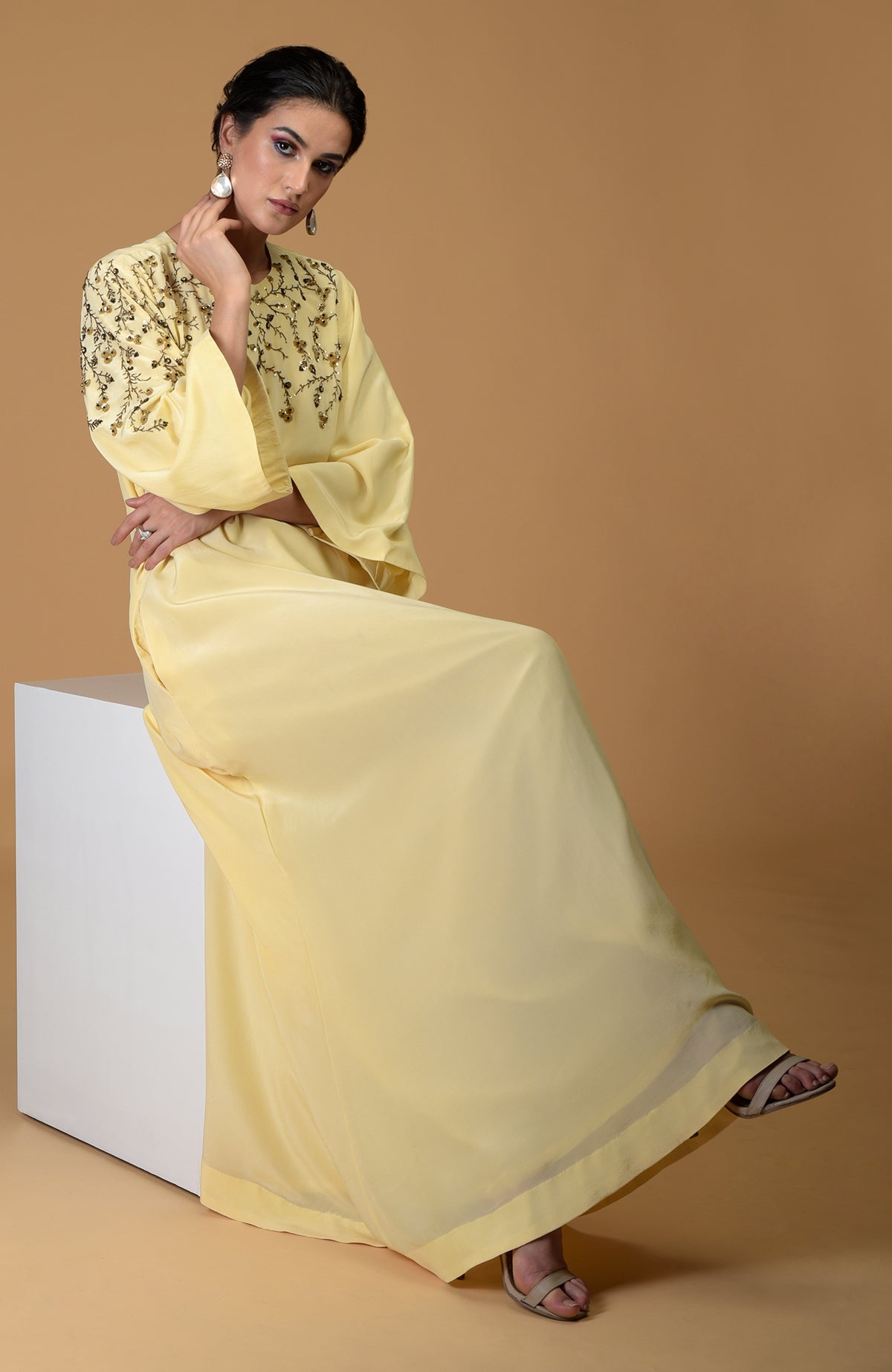 A woman models a lemon yellow dress with dainty floral embroidery.