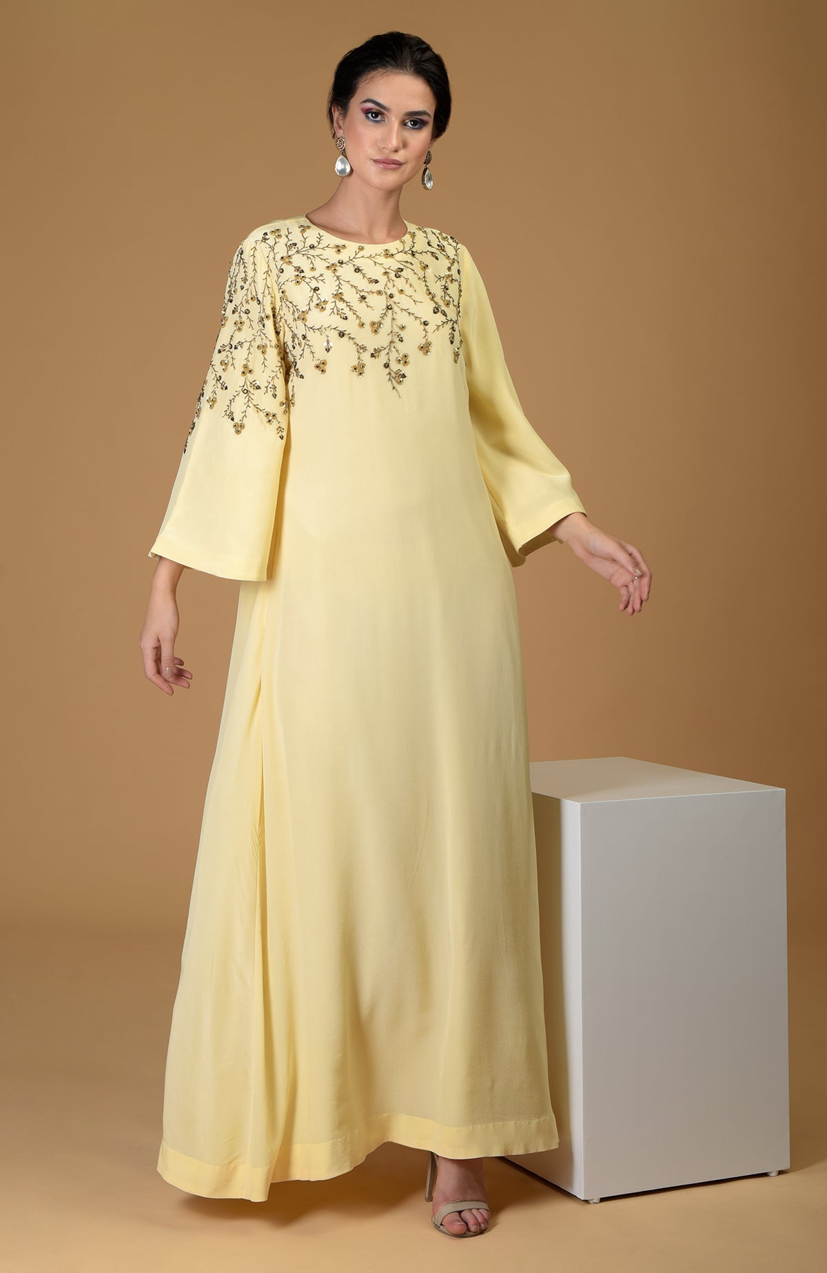 A woman models a lemon yellow dress with dainty floral embroidery on the yoke and sleeve.