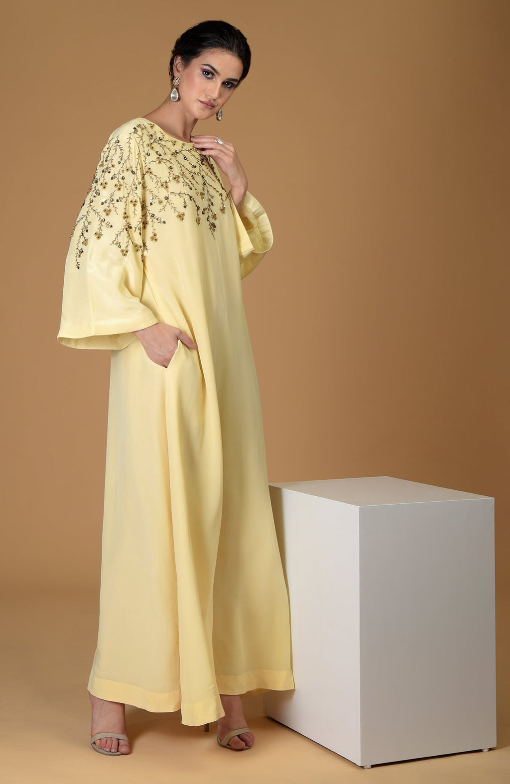 A woman models a lemon yellow dress with delicate floral embroidery on the yoke and sleeve.