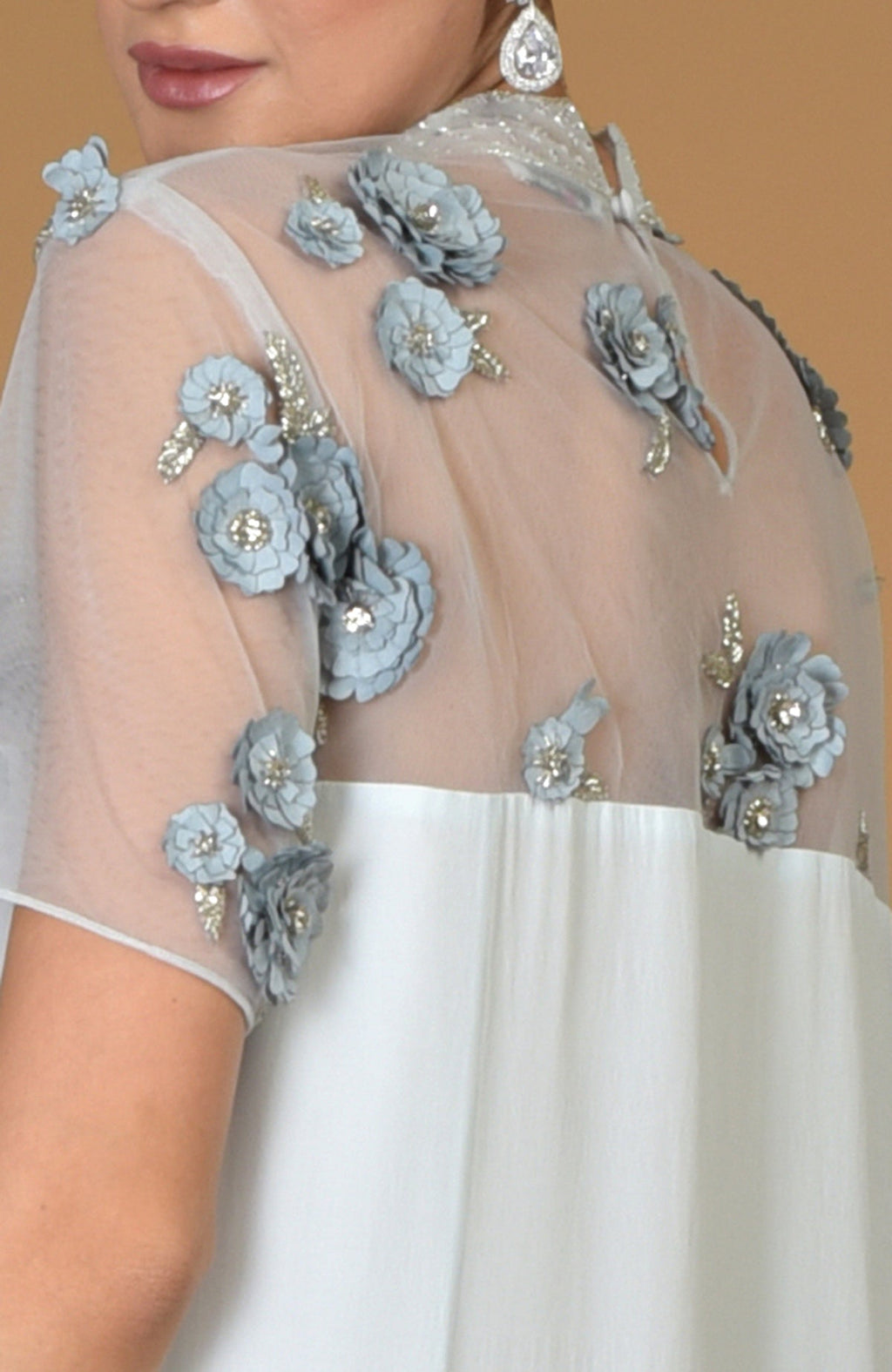 Close-up of a woman wearing a blue twilight hand-embroidered dress with floral appliques.