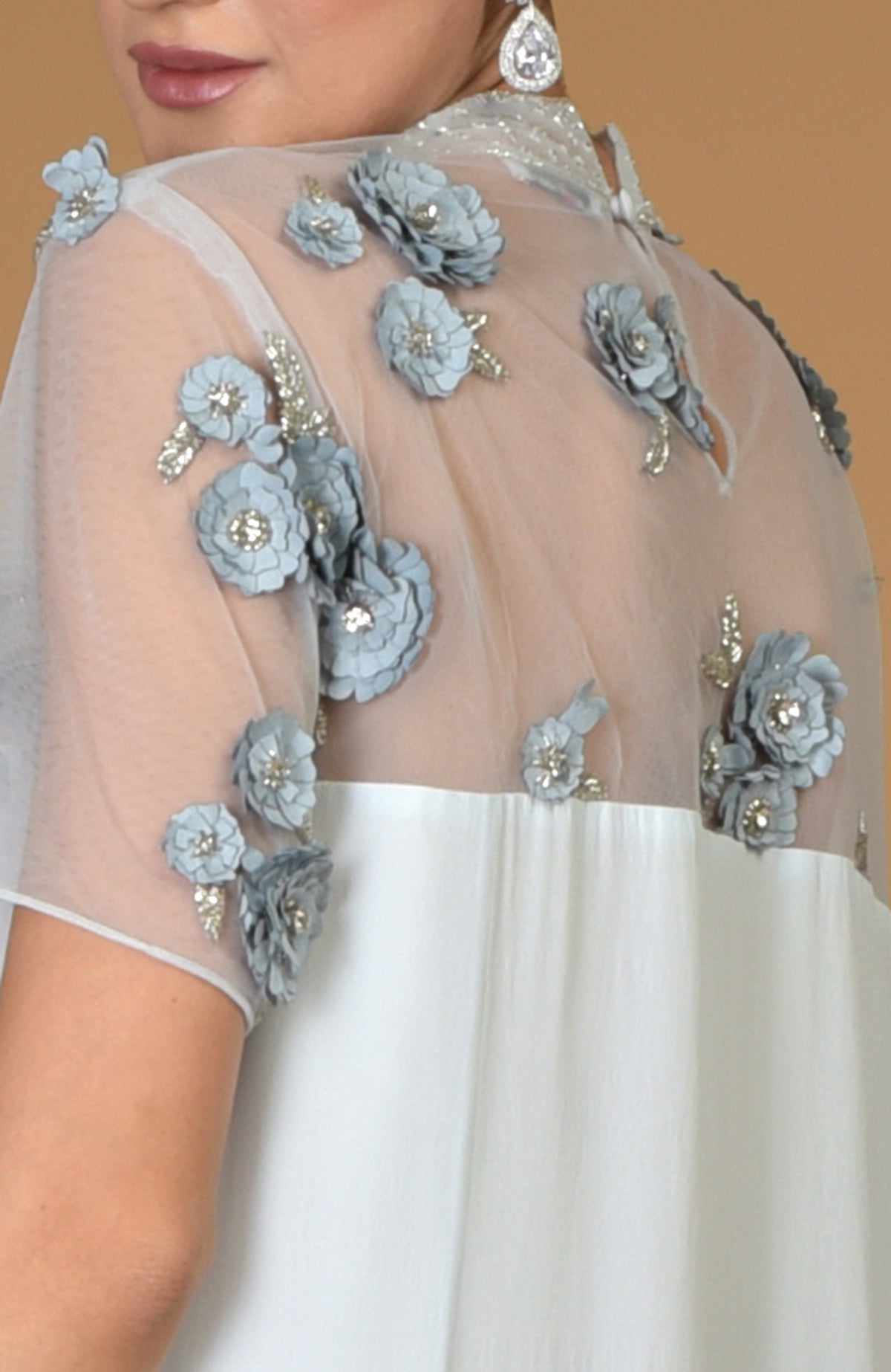 Close-up of a woman wearing a blue twilight hand-embroidered dress with floral appliques.