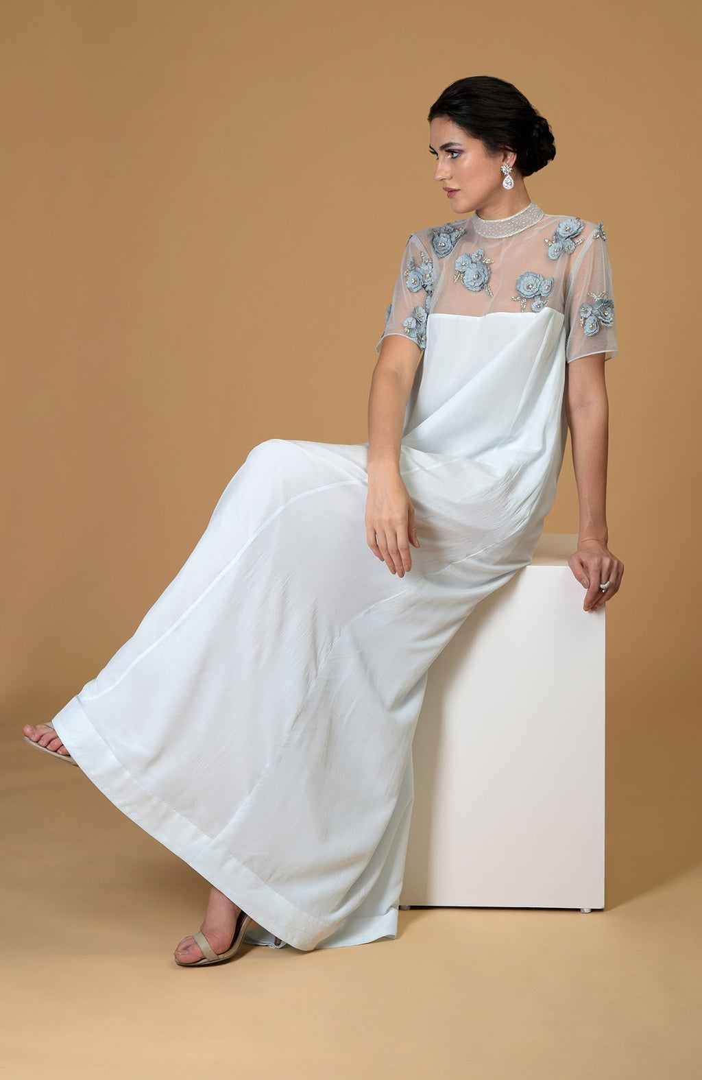 A woman models a light blue dress with sheer embroidered floral details.