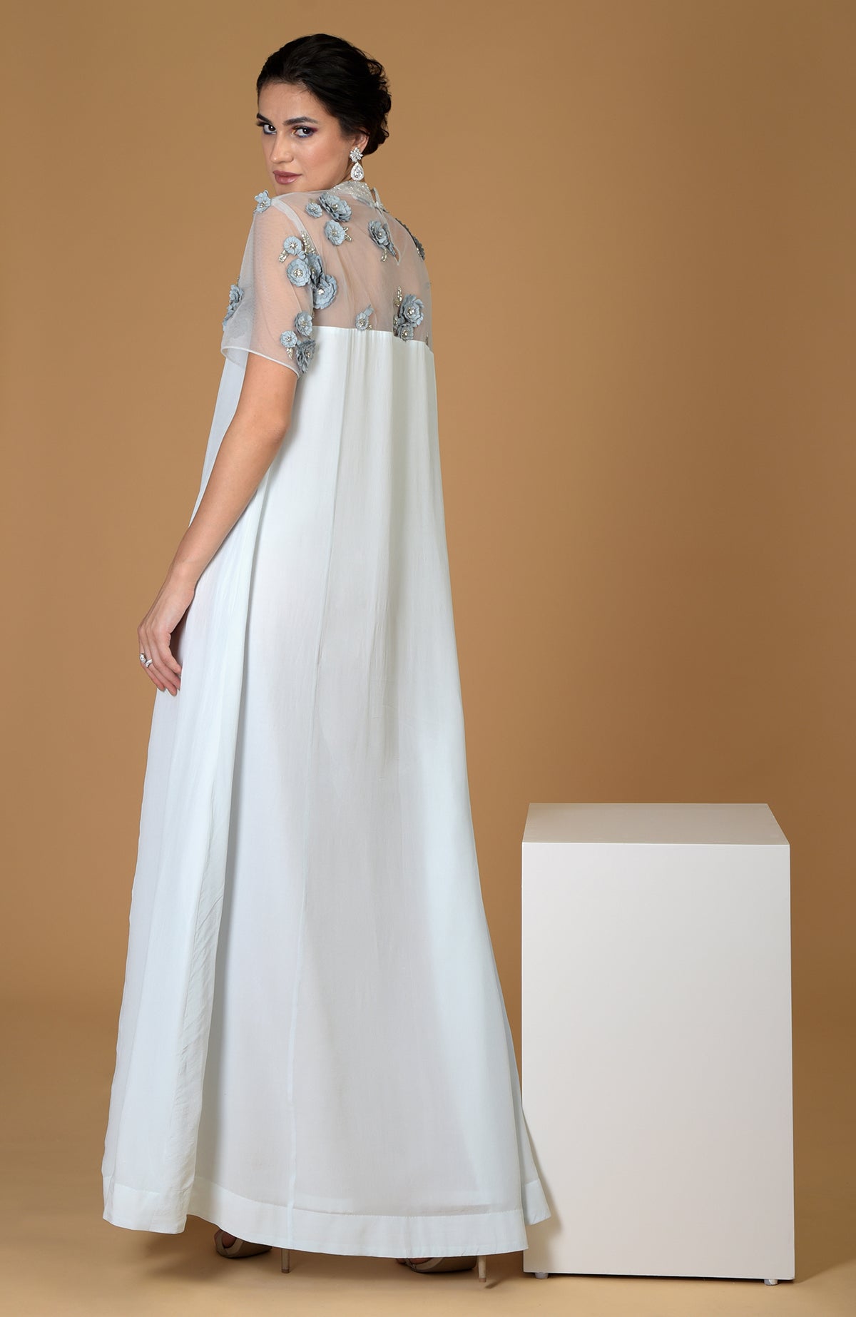 A woman models a blue twilight hand-embroidered dress with floral details.