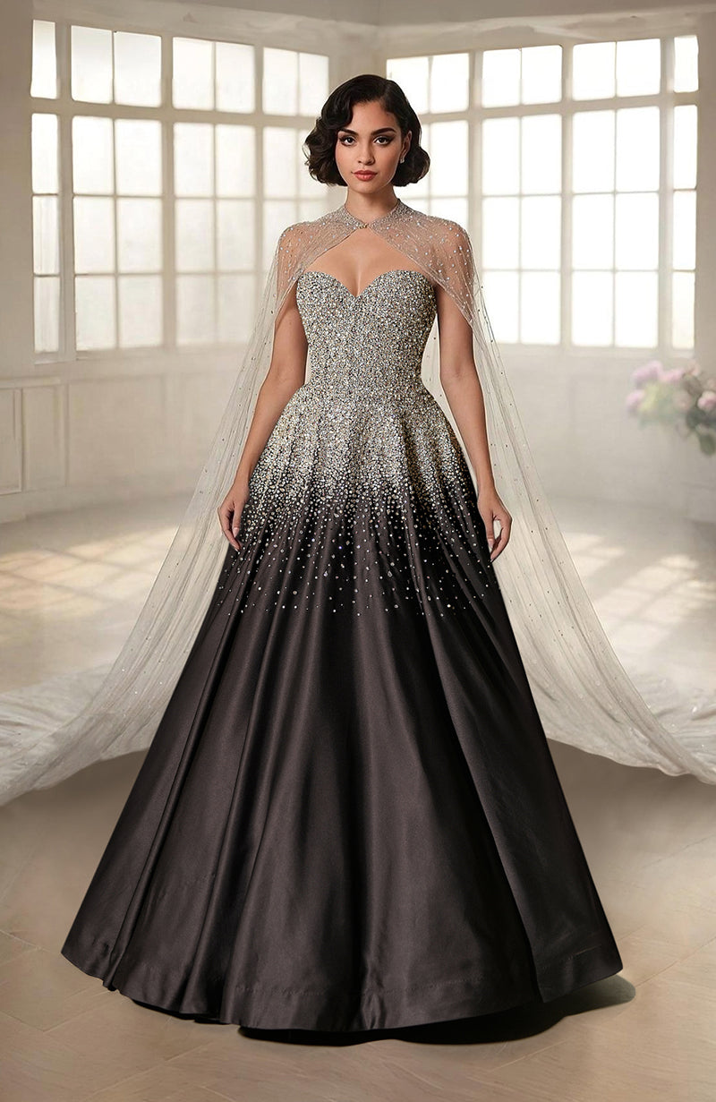 A woman models a black and silver crystal-embroidered princess gown with a sheer cape.