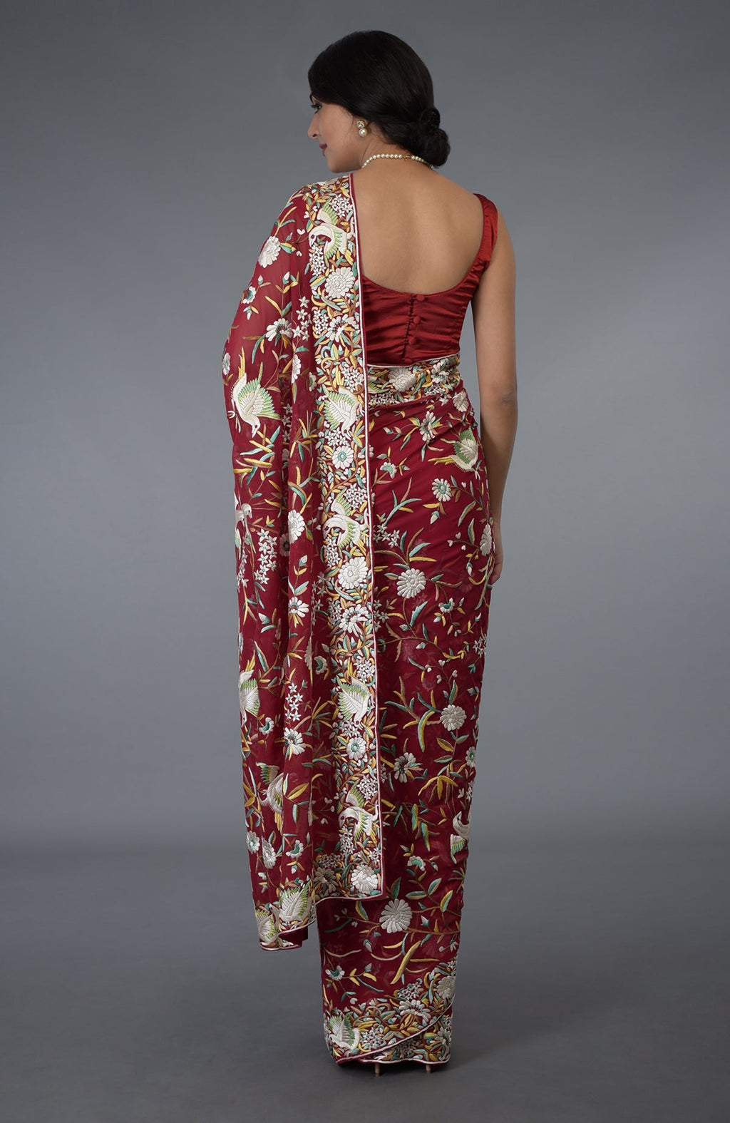 A woman models a red Parsi Gara hand-embroidered saree with bird and floral motifs.