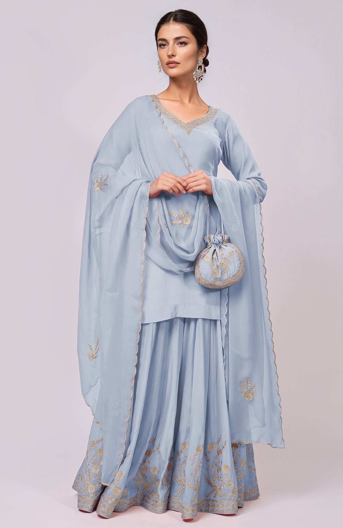 A woman models a dusty blue sharara set with gold Kashmiri Tilla Aari embroidery.