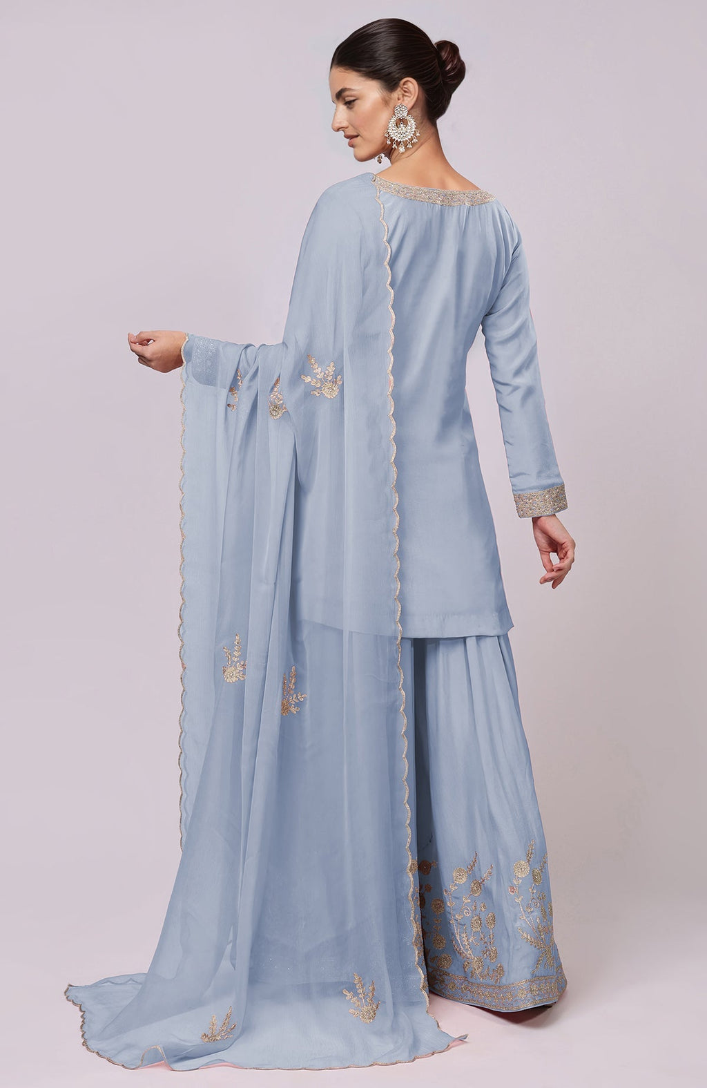 A woman models a dusty blue Kashmiri Tilla Aari embroidered sharara set.