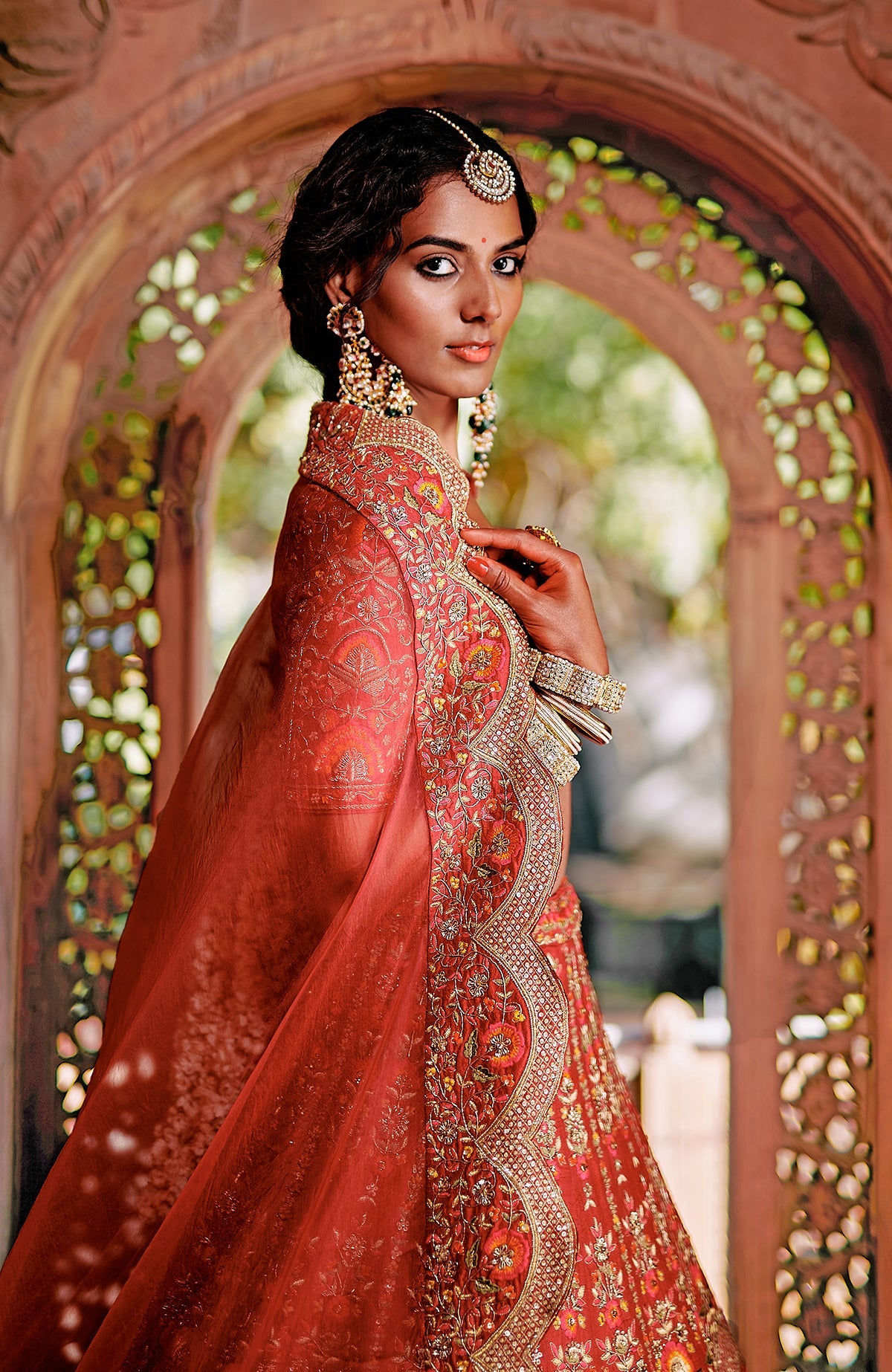 Red lehenga set with intricate gold embroidery, floral motifs, peacock tassels, and sheer dupatta.