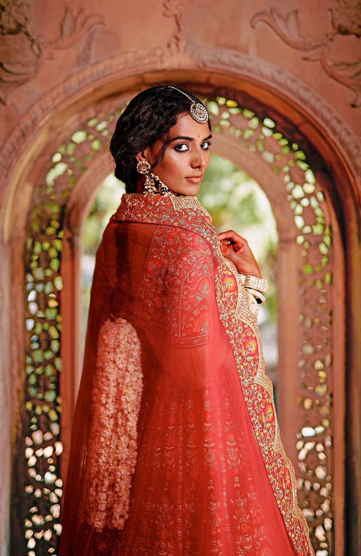 Red lehenga set with intricate floral embroidery, gold detailing, peacock tassels, and scalloped dupatta.