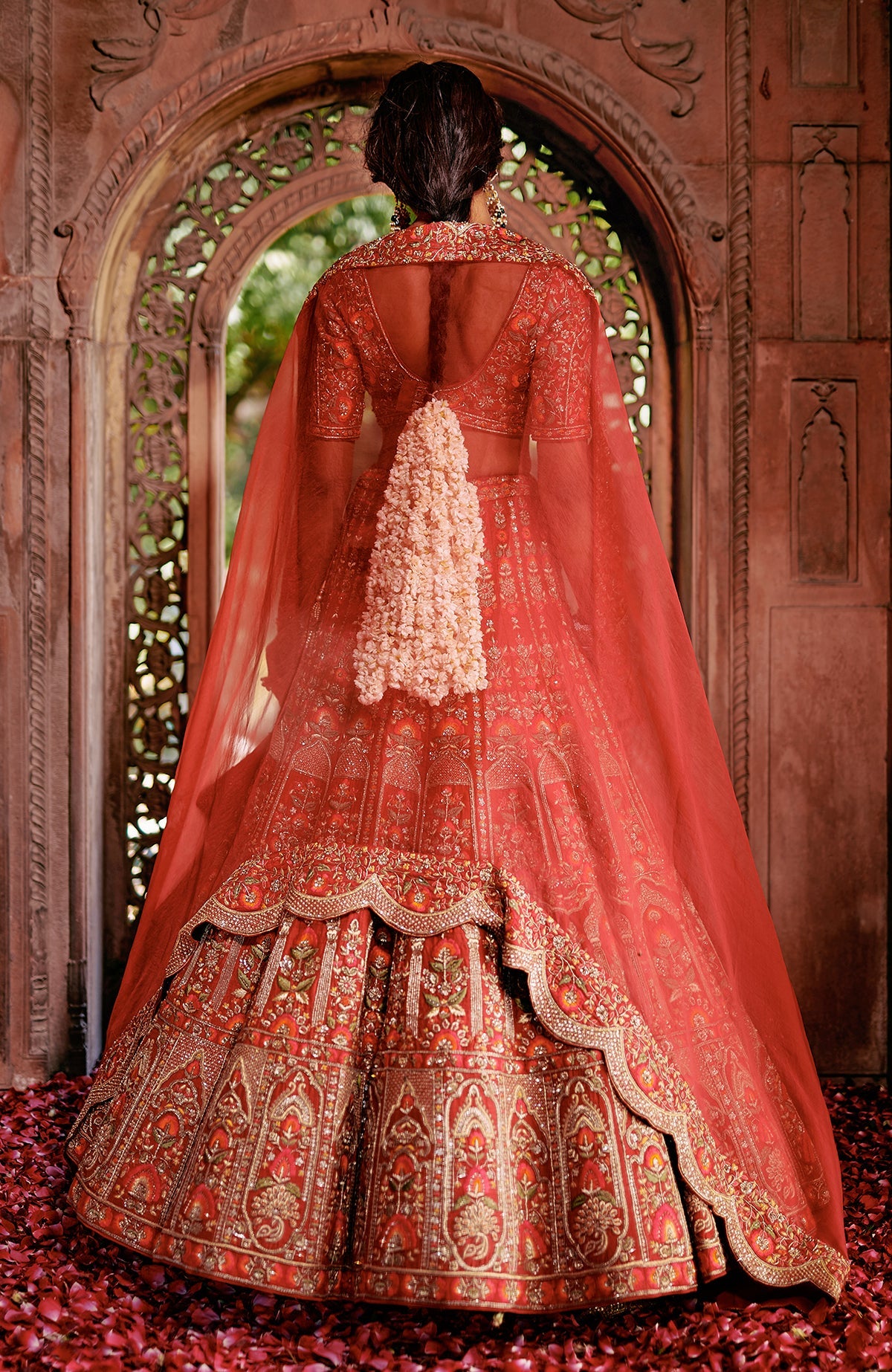 Red lehenga set with intricate gold embroidery, peacock tassels, and a sheer scalloped dupatta.