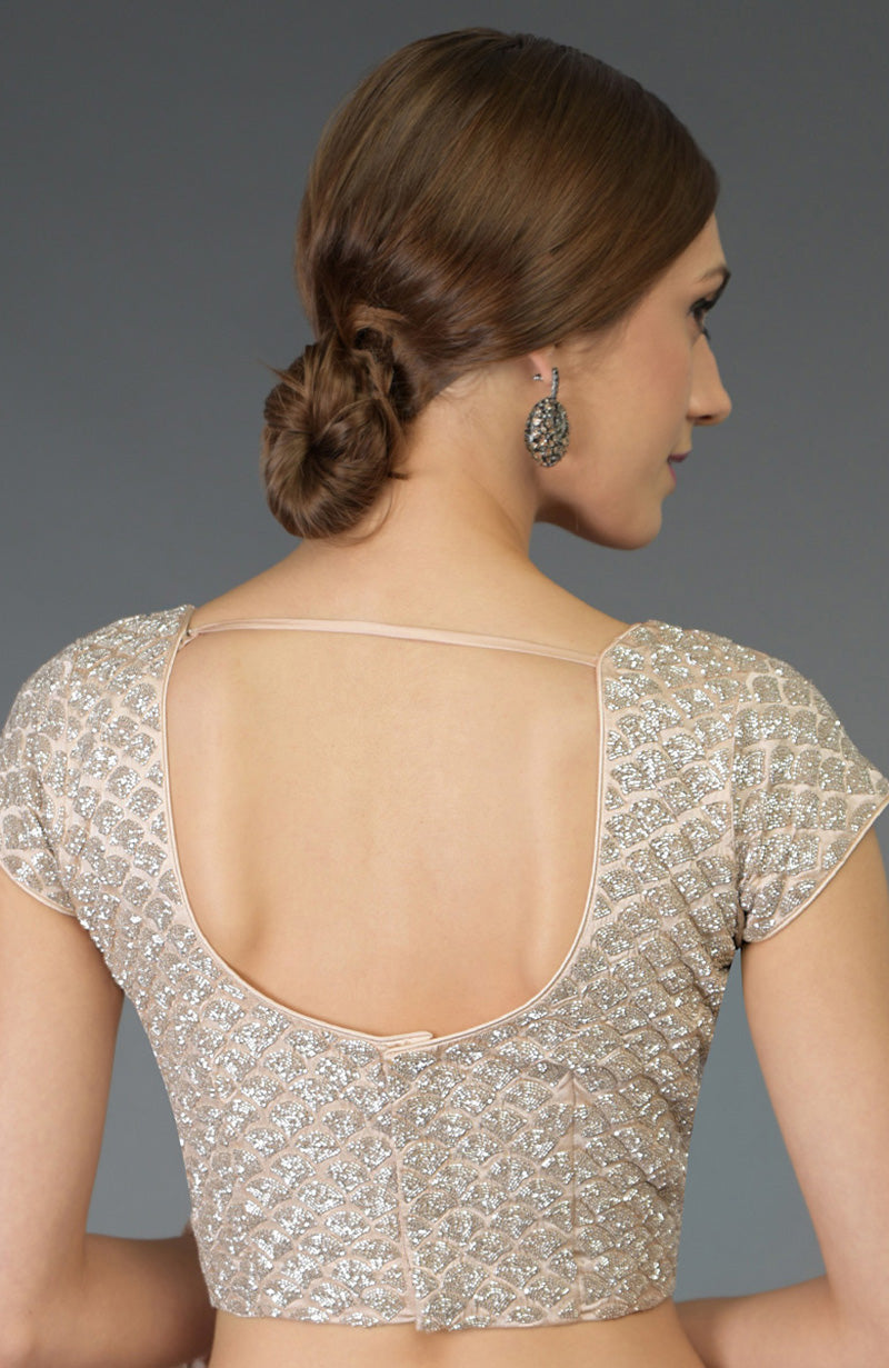 A woman models a nude peach zardozi hand-embroidered blouse with a deep U-shaped back.