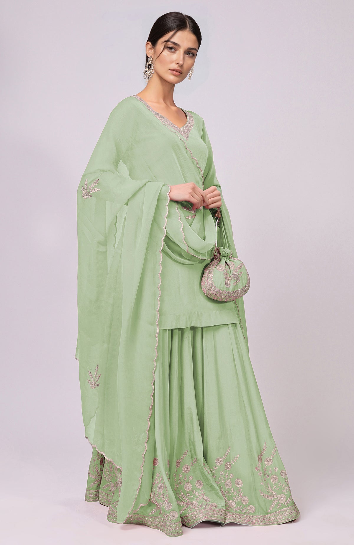 A woman models a sage green sharara set with Kashmiri Tilla Aari embroidery.