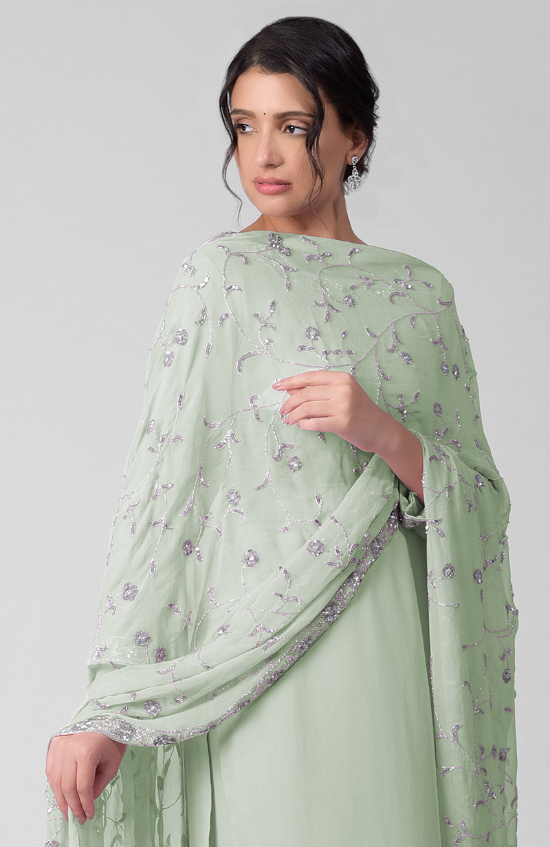 A woman models a mist green kurta set with silver beads and sequin zardozi embroidery.
