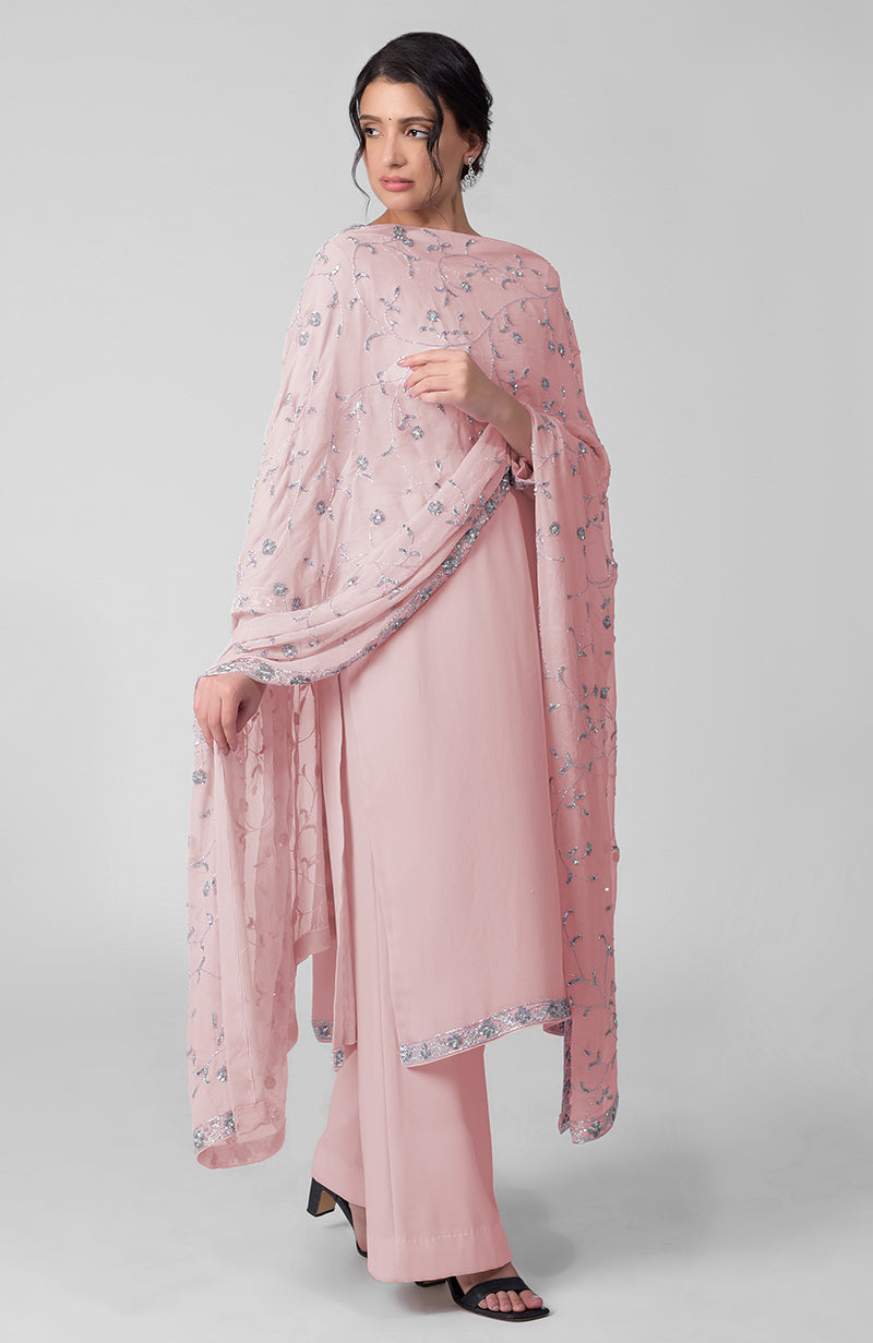 A woman models a pink kurta set with silver beads and sequin zardozi embroidery.