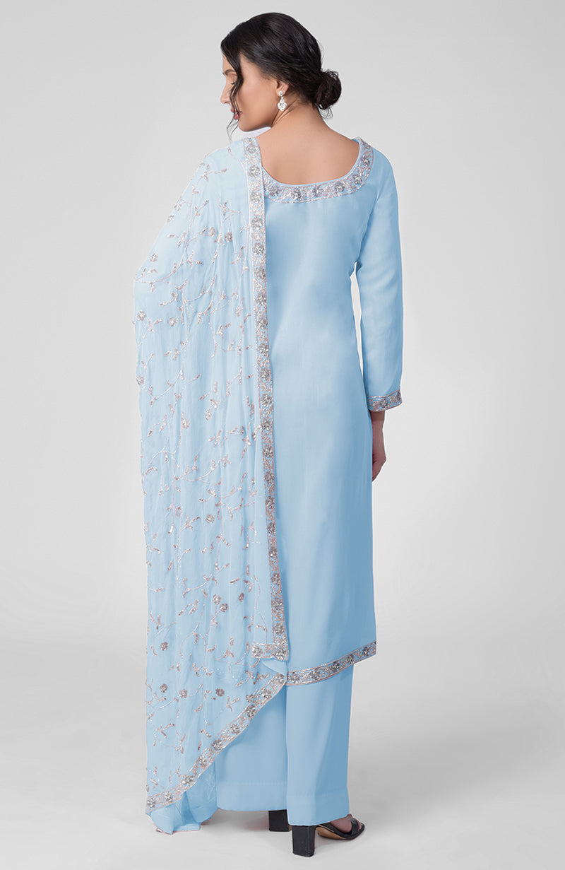 A woman models a delicate blue kurta set with silver embroidery and a matching dupatta.