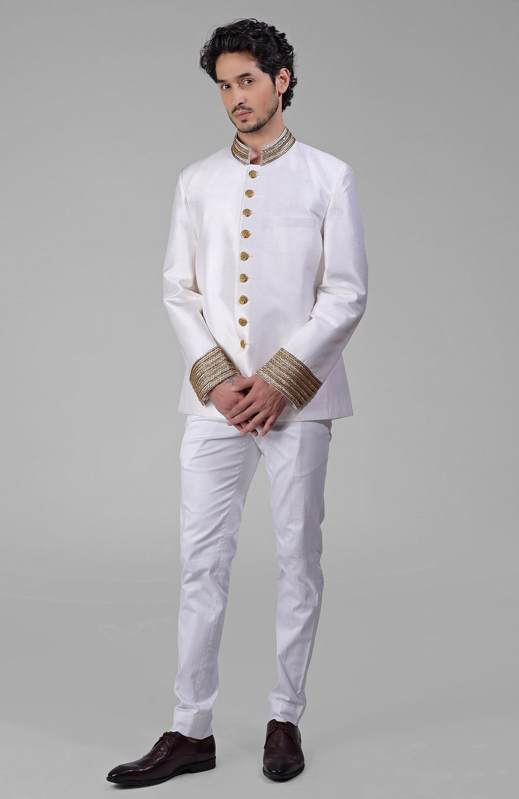 An ivory-gold zardozi hand-embroidered silk bandhgala jacket with matching pants and brown shoes.
