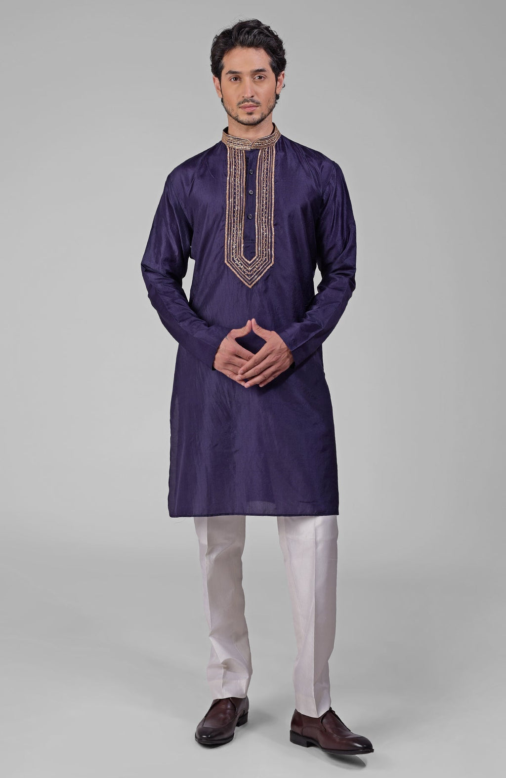 A man models a blue silk kurta set with intricate gold embroidery on the placket.