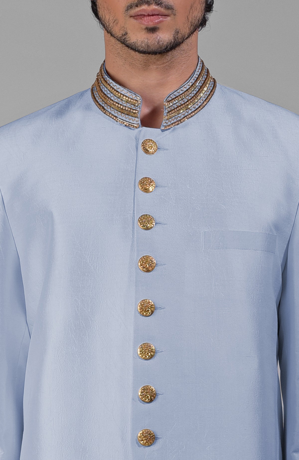 Dusty blue silk bandhgala jacket with gold zardozi embroidery and golden button closure paired with white pants