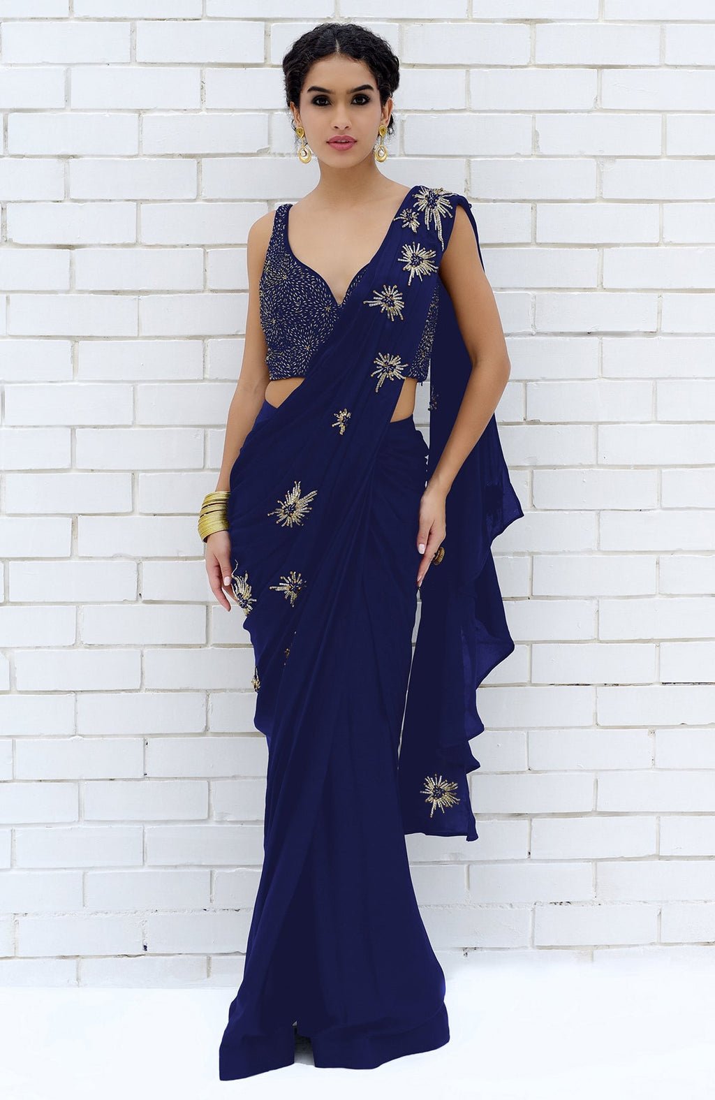 A woman models a royal blue saree with gold starburst embroidery and a matching blouse.