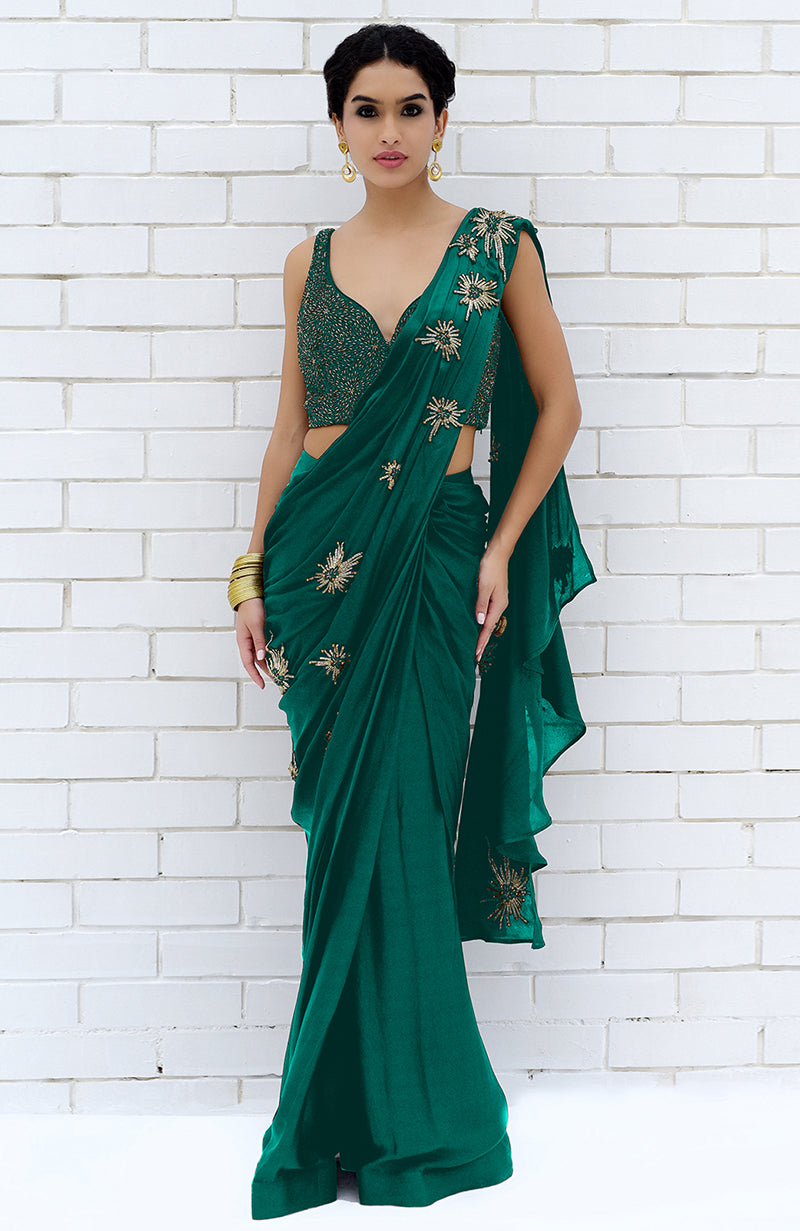 An emerald green saree with gold starburst embroidery and a matching beaded blouse.