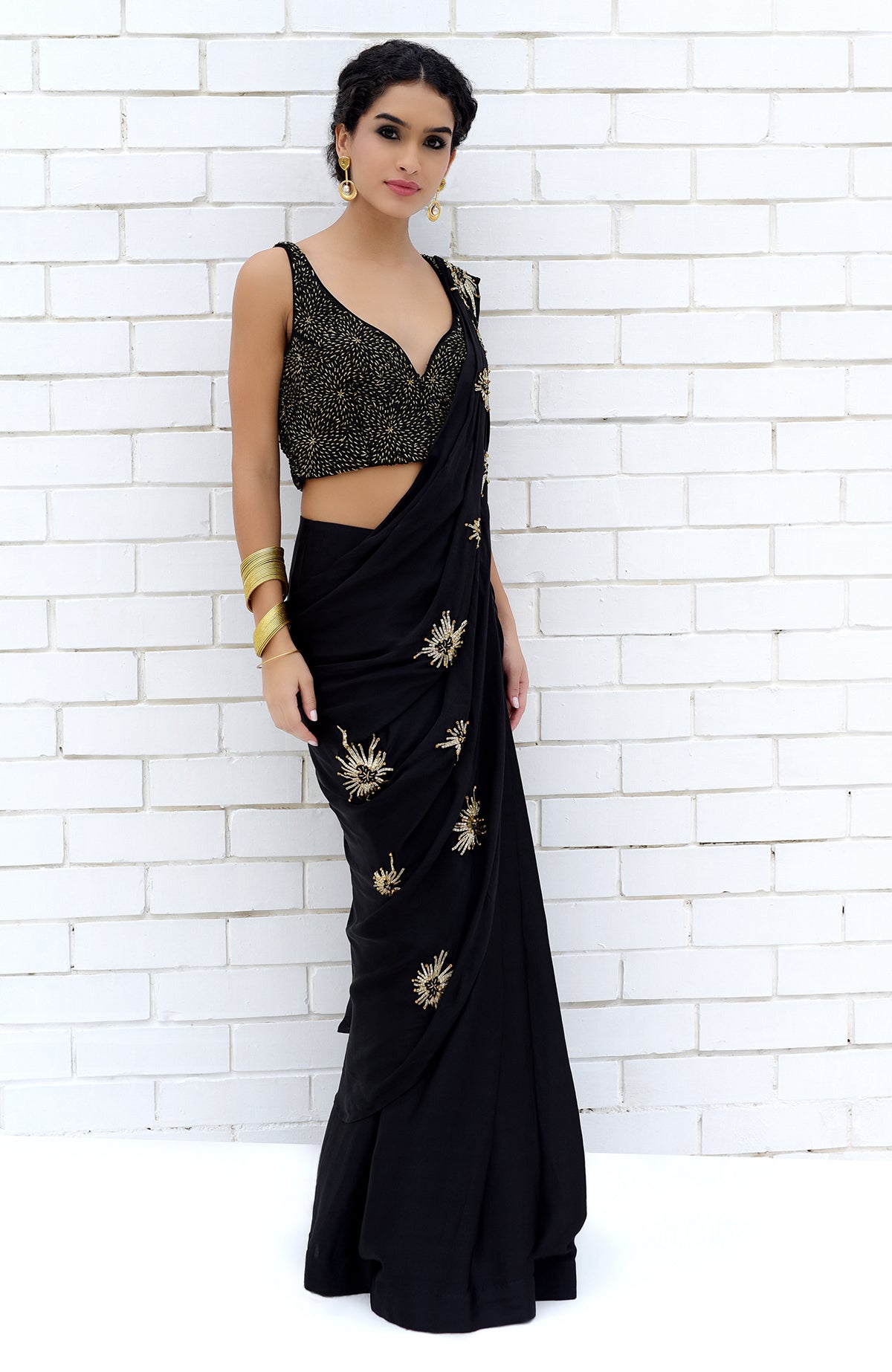 Black pre-draped saree with a gold embroidered blouse and starburst motifs.