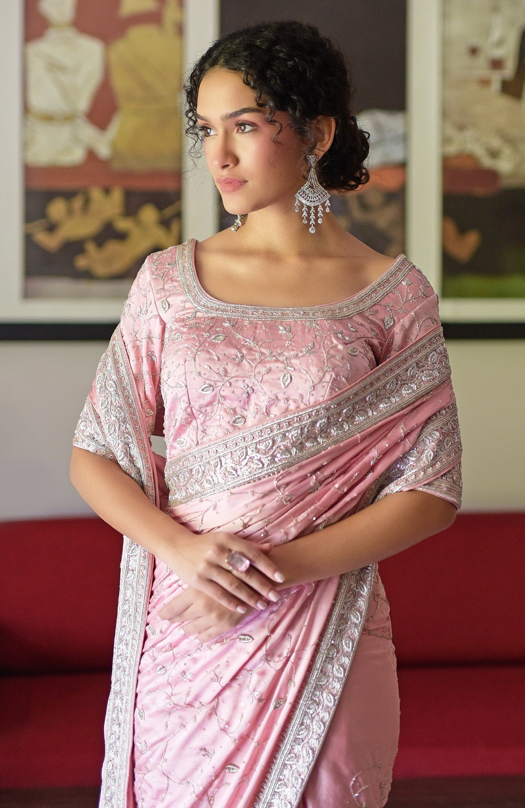 A woman in a pink silk saree with silver zardozi embroidery and a matching blouse.
