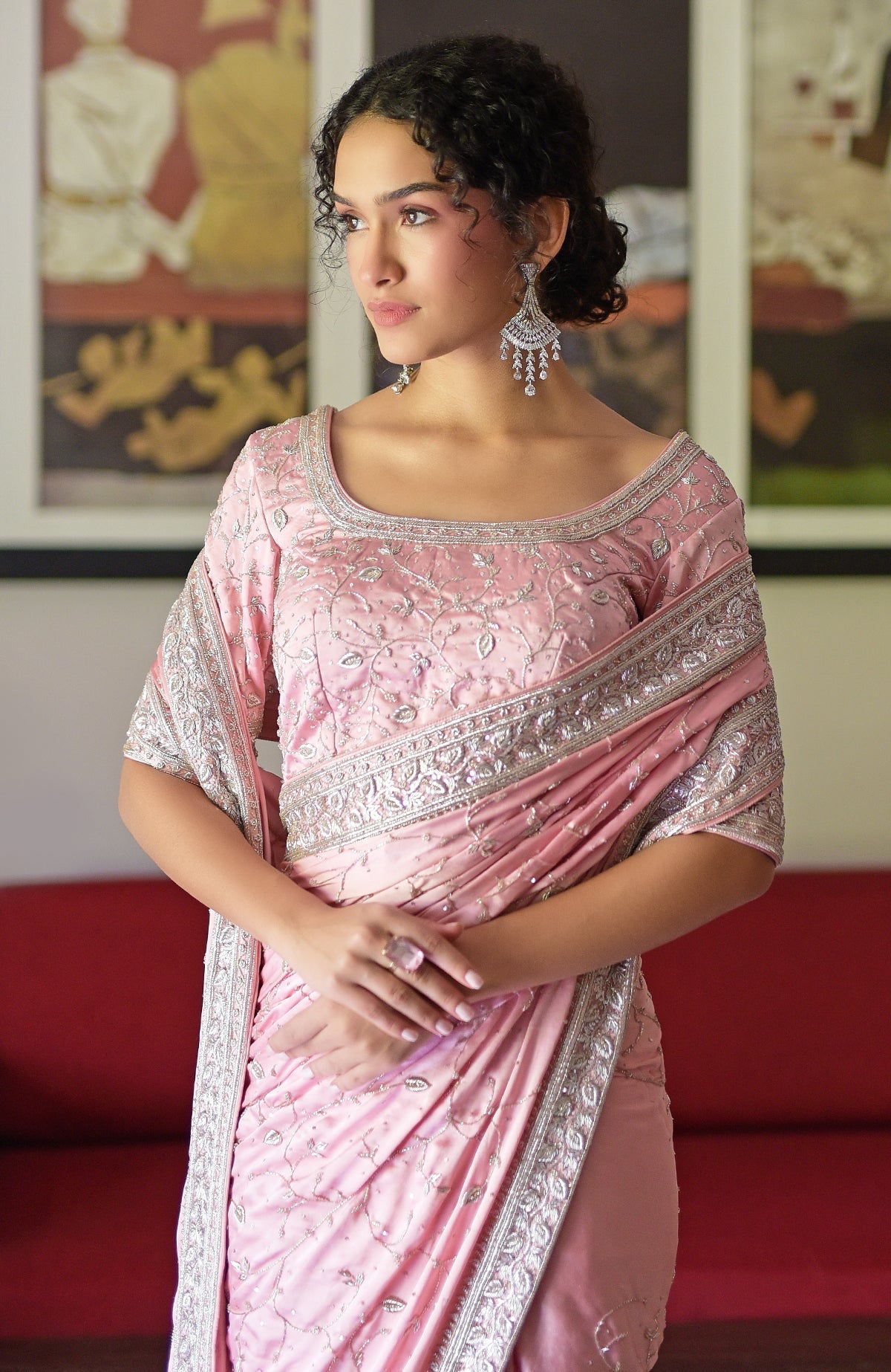 A woman in a pink silk saree with silver zardozi embroidery and a matching blouse.