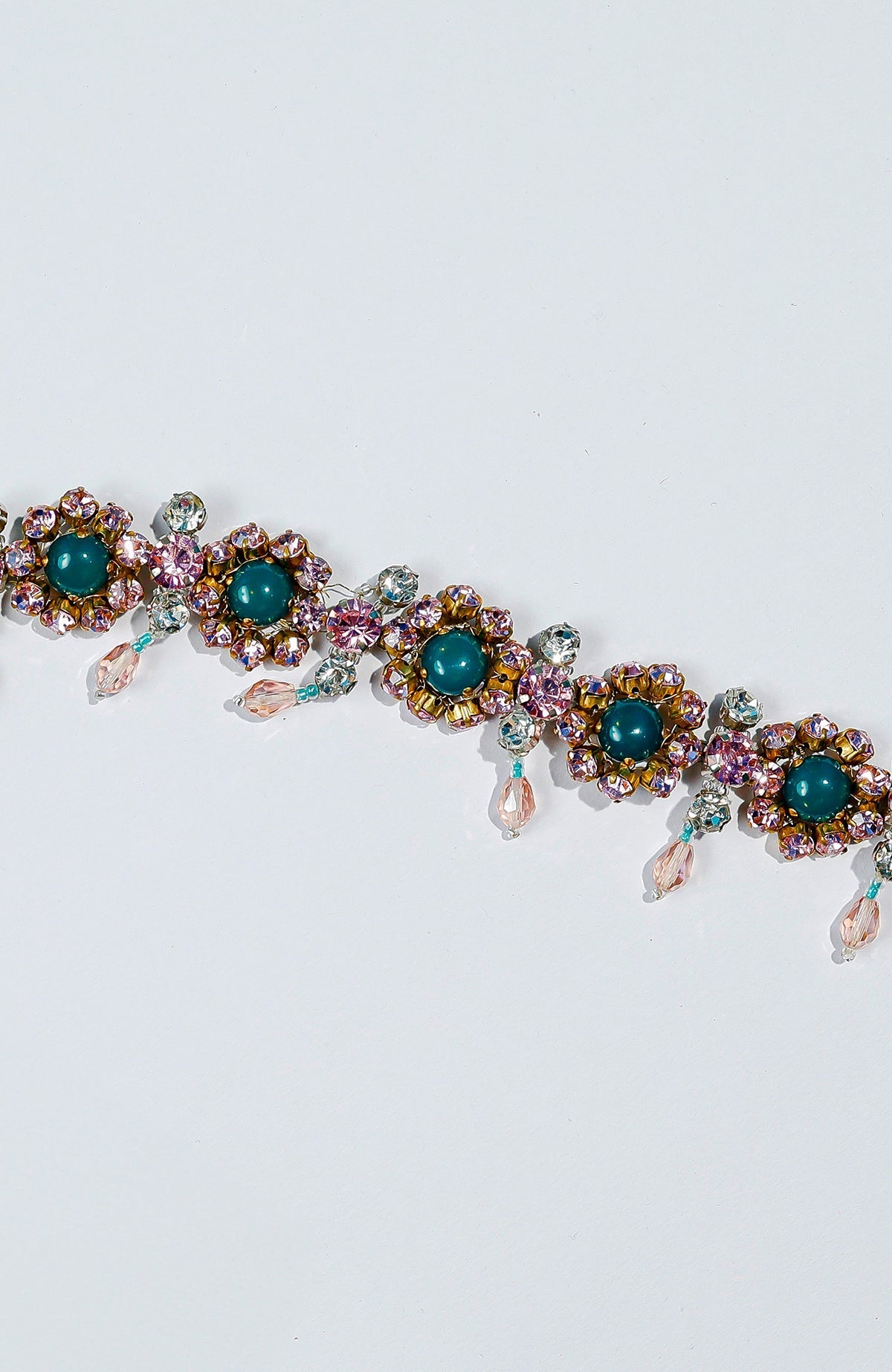 Pink belt adorned with green and pink crystals and golden dangling stones.