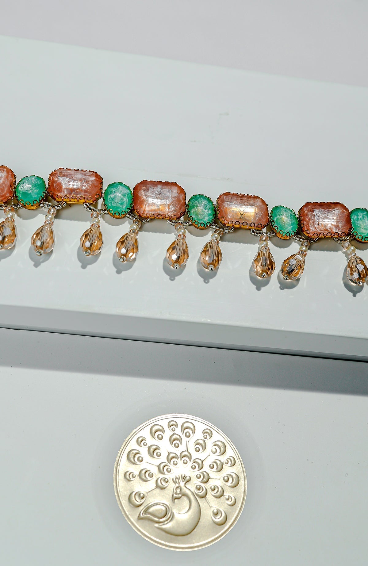 Multi-colored crystal belt with green and pink stones and golden dangling accents.