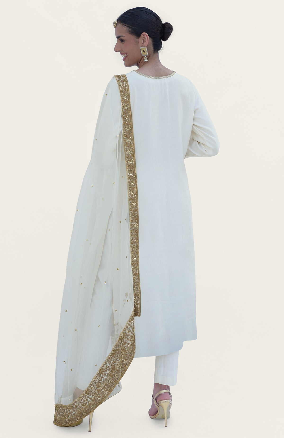 An elegant woman in an ivory-gold marori beads and sequin hand-embroidered kurta set.