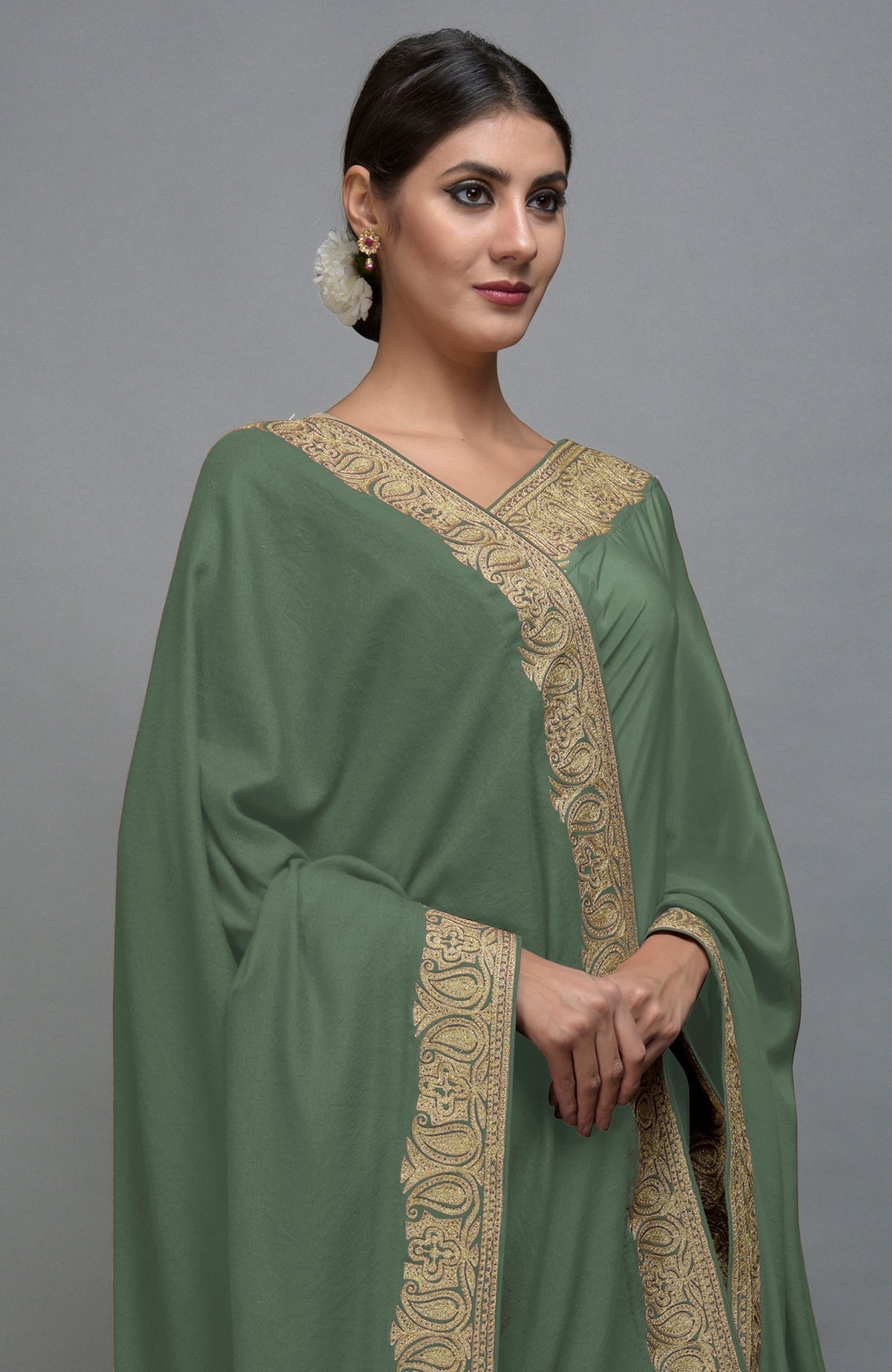 Dark jade pashmina shawl with gold paisley embroidery worn by a woman.