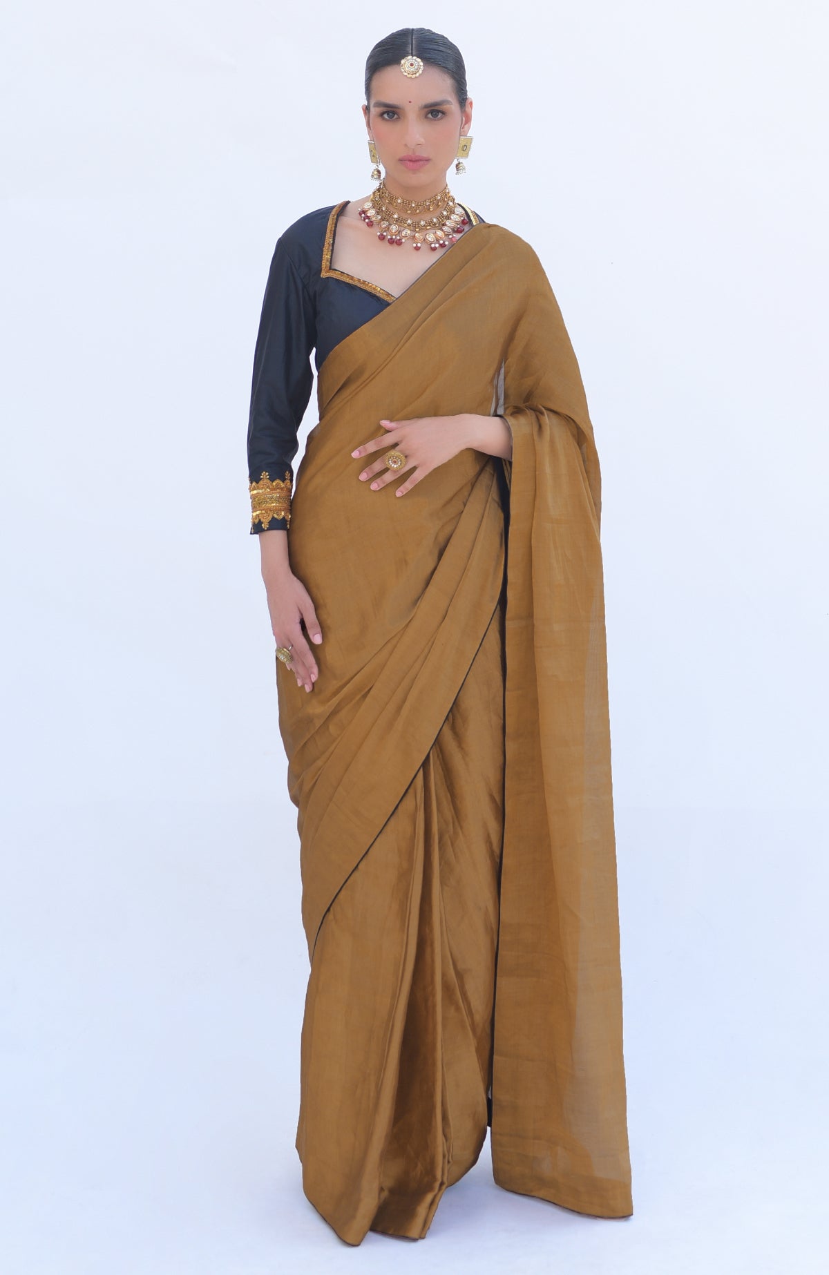 A woman models a gold tissue saree with a black zardozi embroidered blouse.