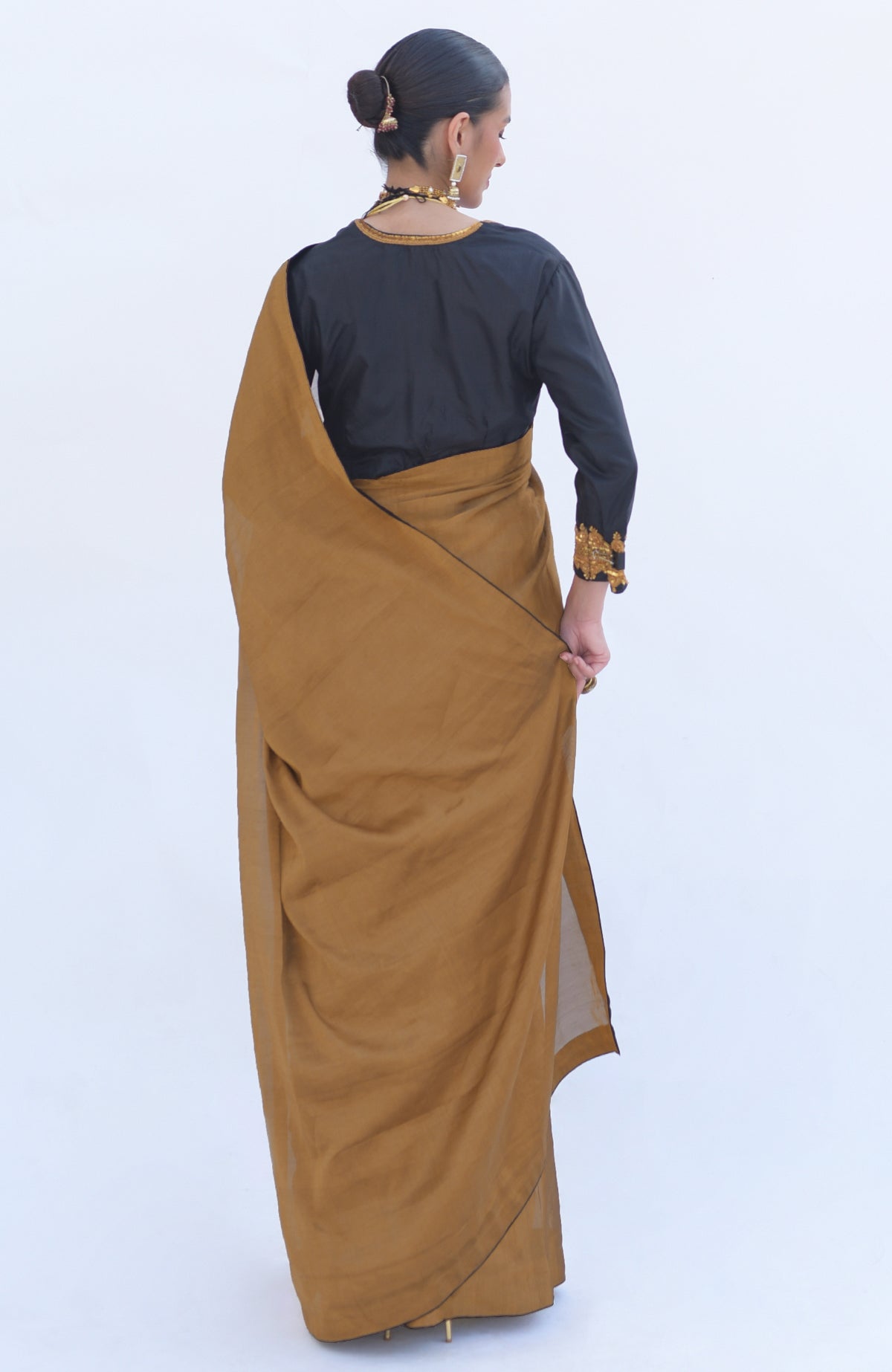 Woman in a gold tissue saree with a black zardozi embroidered blouse.