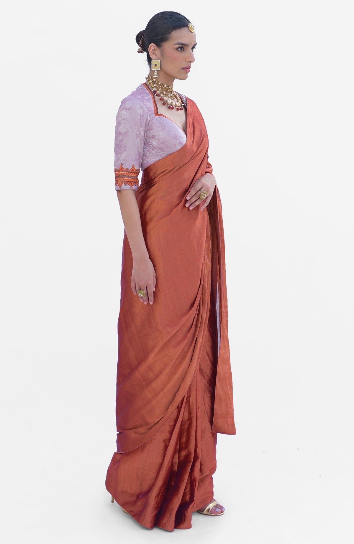 A woman models a pre-stitched copper tissue saree with a zardozi embroidered blouse.